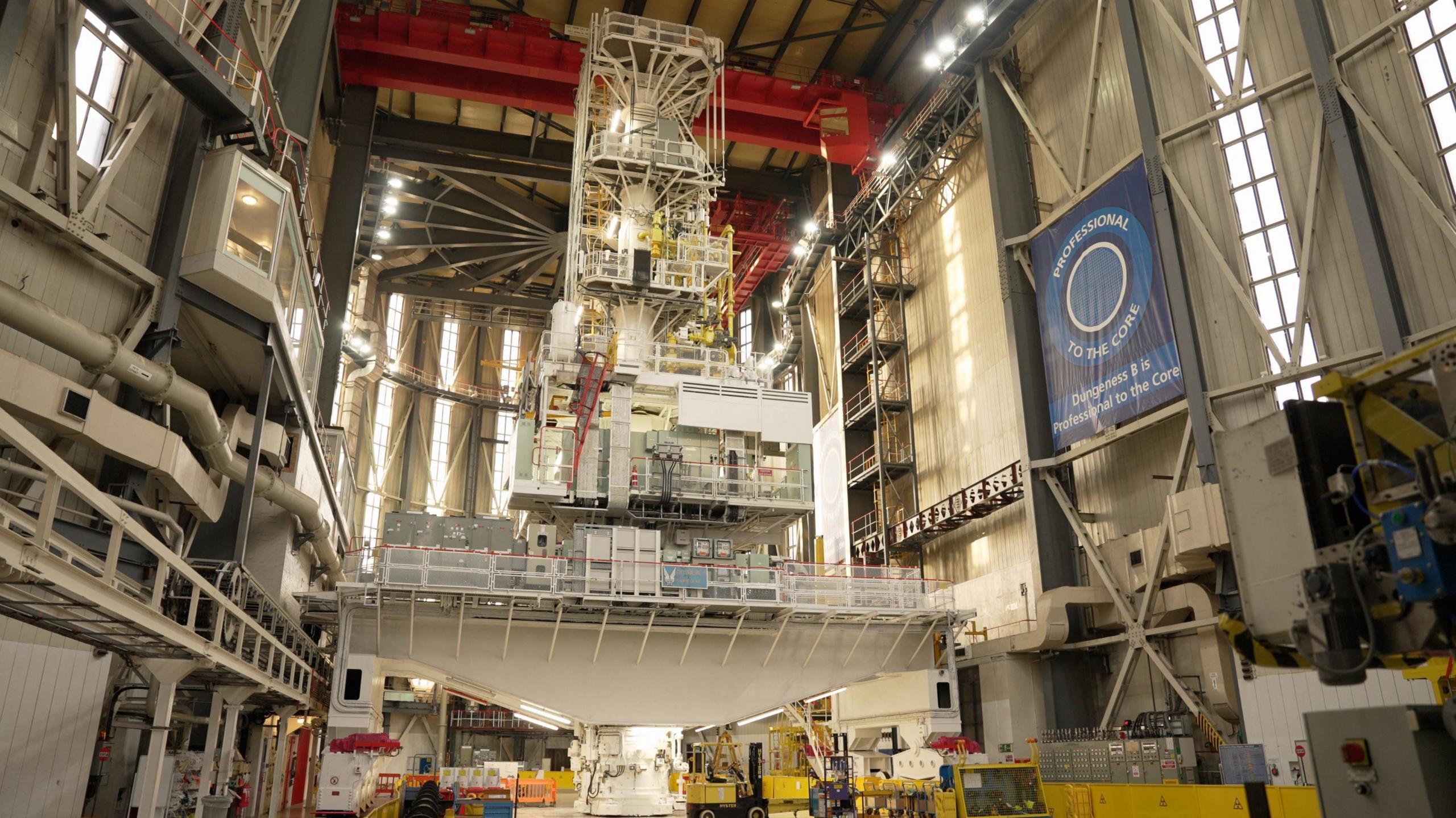 A view of the crane from the ground. It is white and nearly reaches the ceiling.