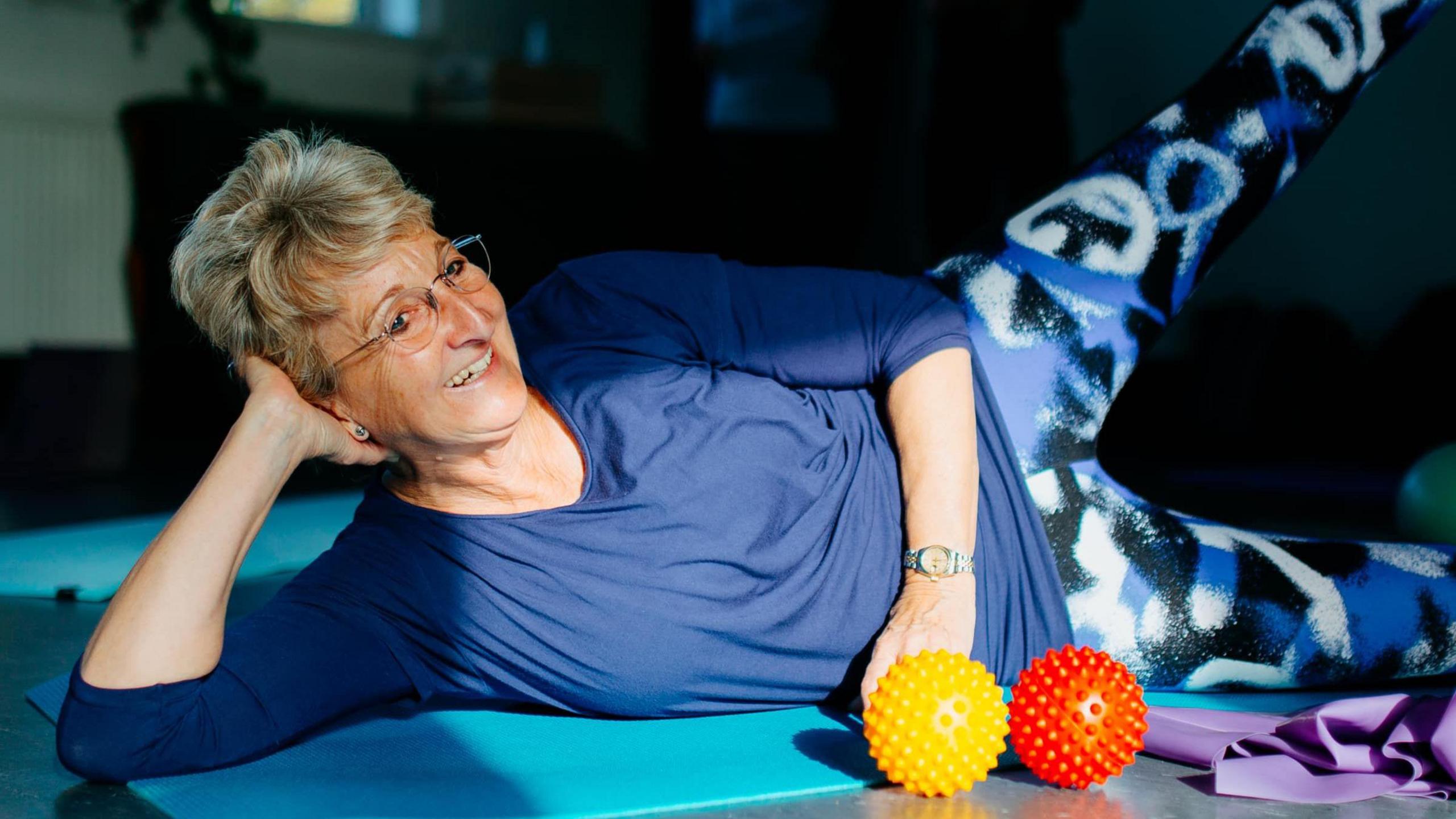 A pilates instructor, Gillian Burn, demonstrating an exercise and smiling