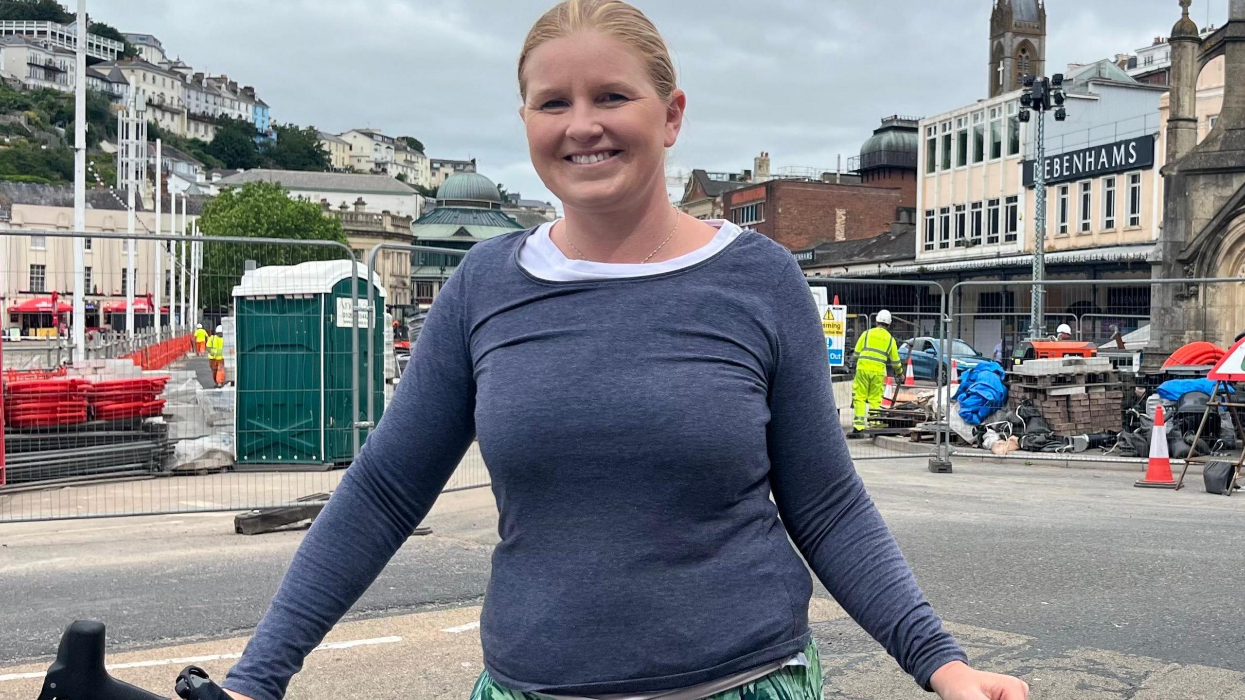 Beth Huntley with her bicycle in front of the regeneration works in Torquay