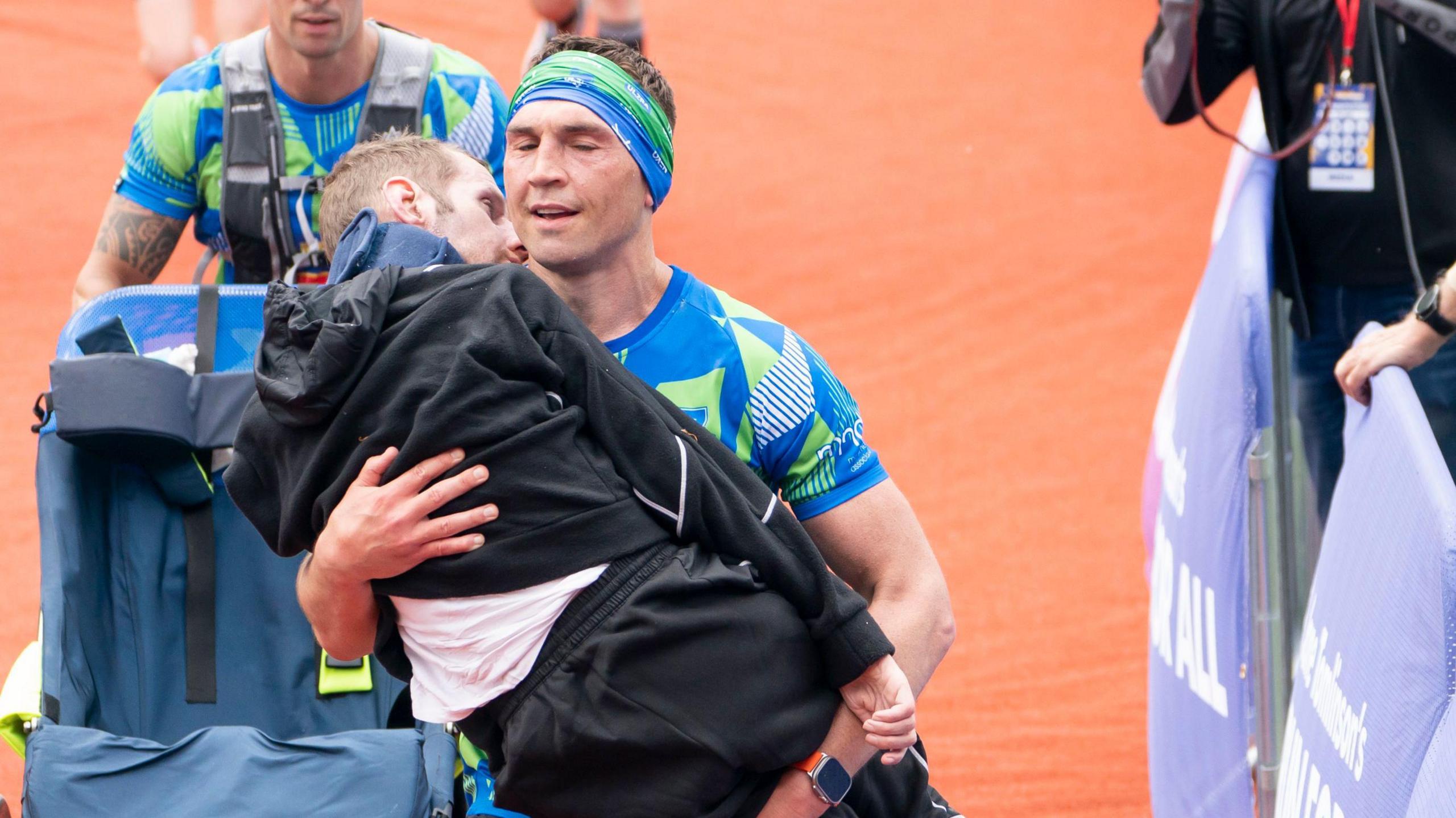 Sinfield carrying Burrow in an embrace as he crosses the finish line after a marathon