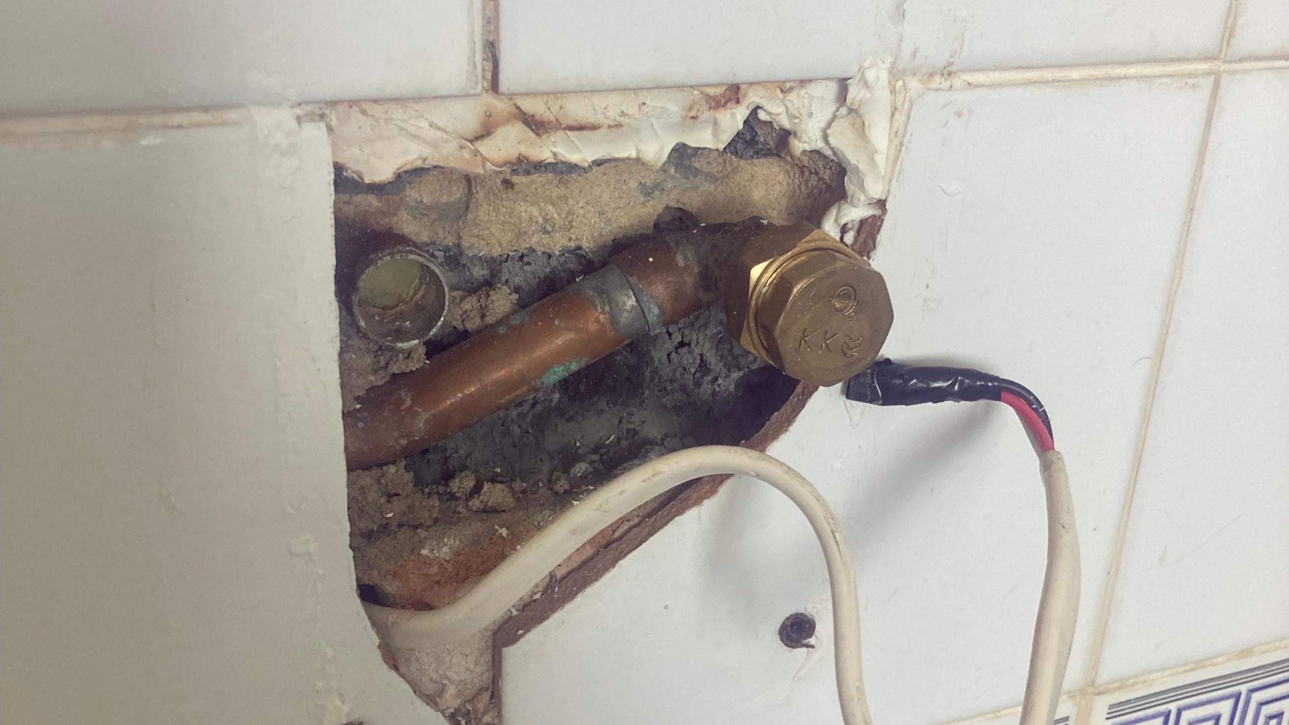 A picture of the shower fitting and exposed pipe in Hayley's bathroom