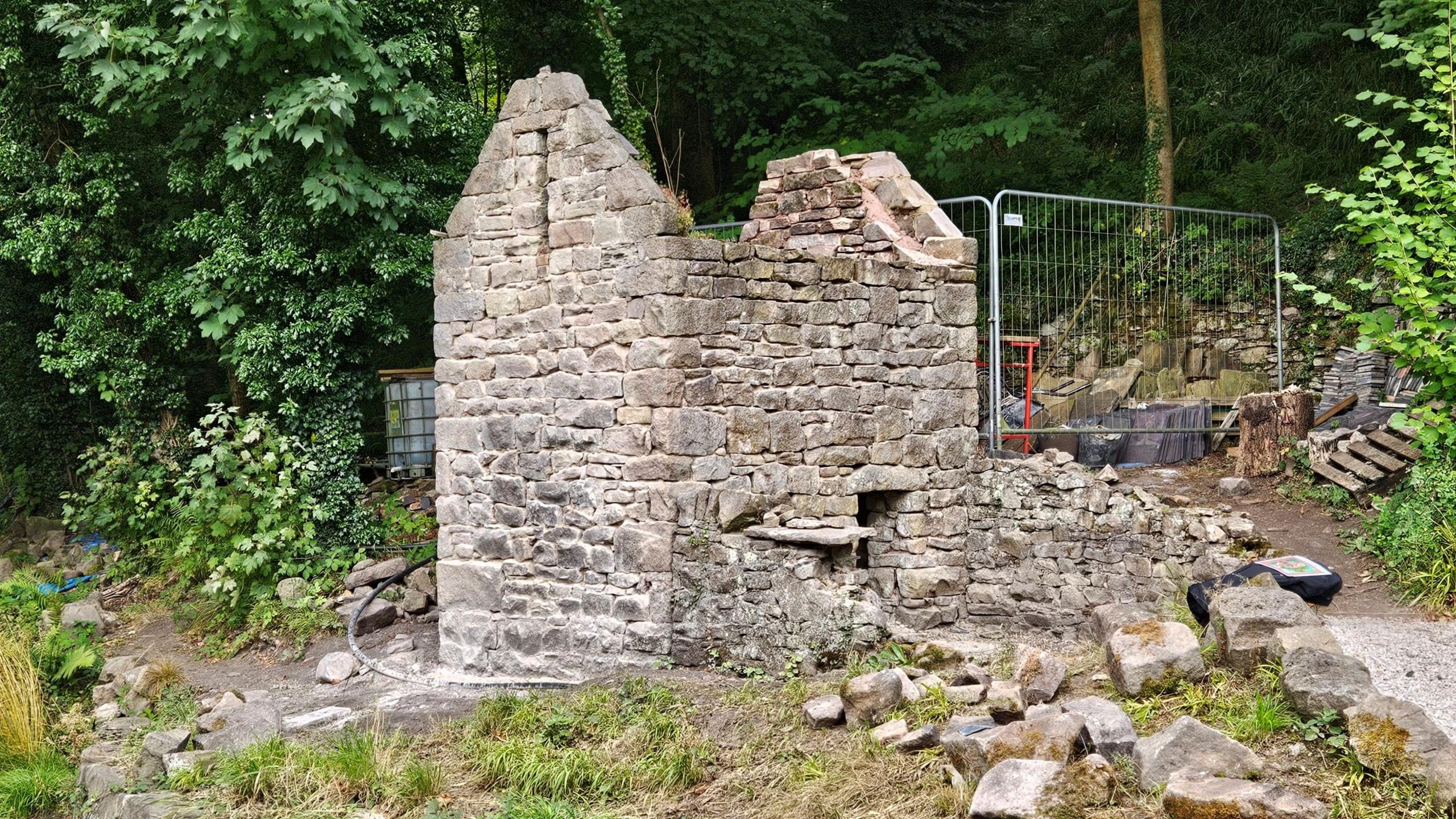 A brick structure which used to be a privy and pigsty outbuilding with its roof missing and bricks on the ground. It is currently being restored