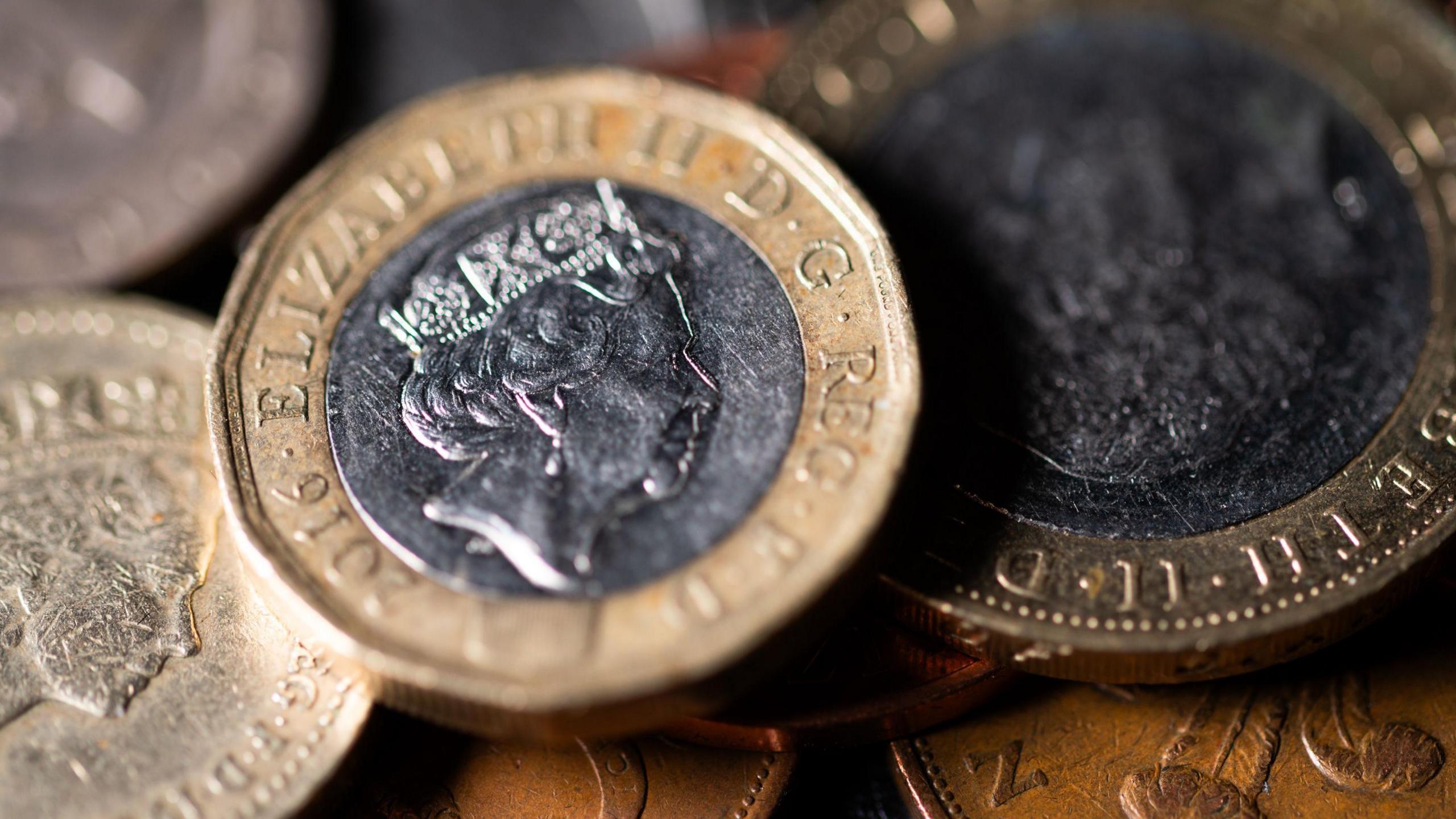 Various coins with the Queen's face on them, piled up.