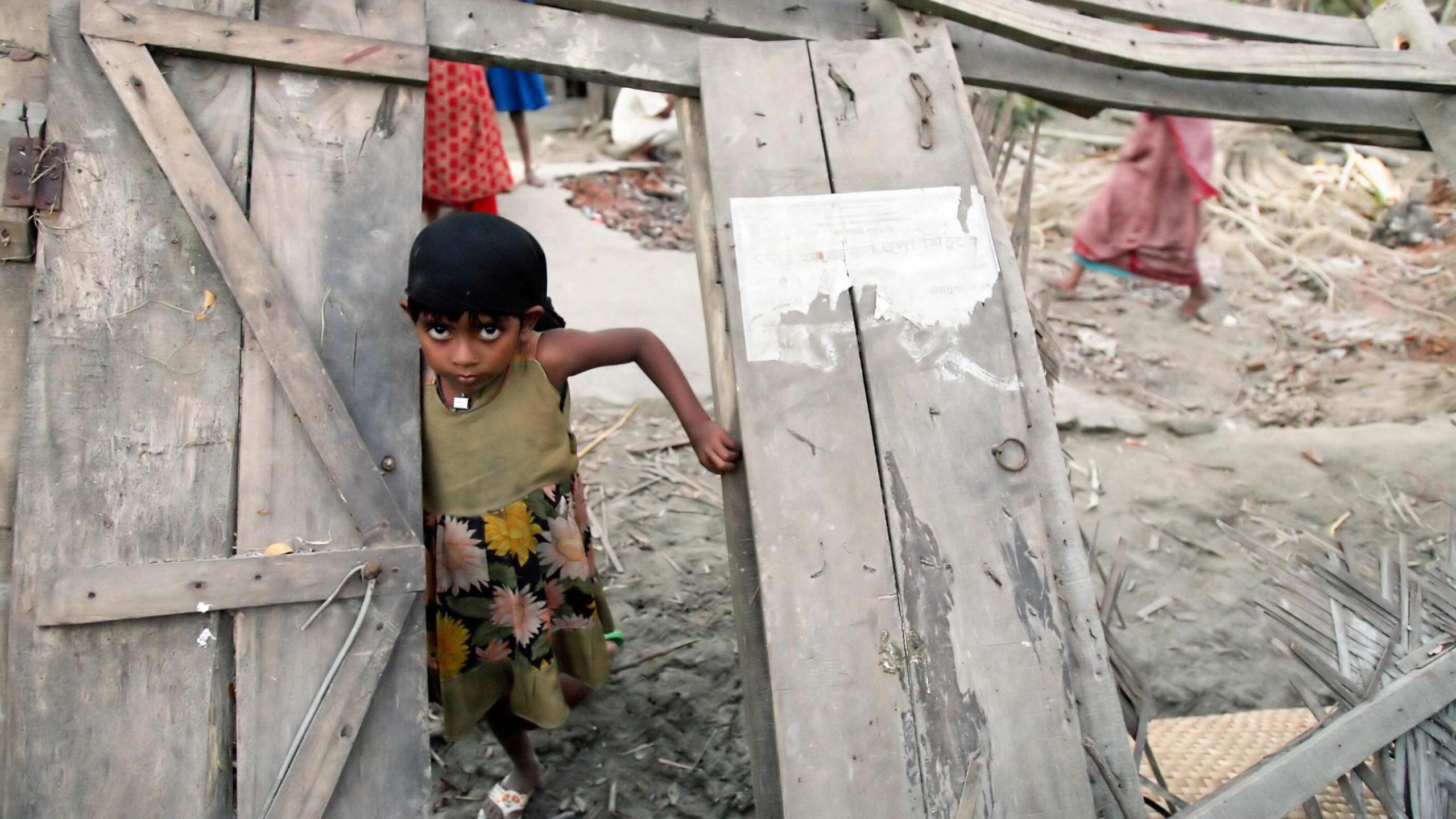 A Bangladeshi cyclone-affected girl is framed with her destroyed house's door