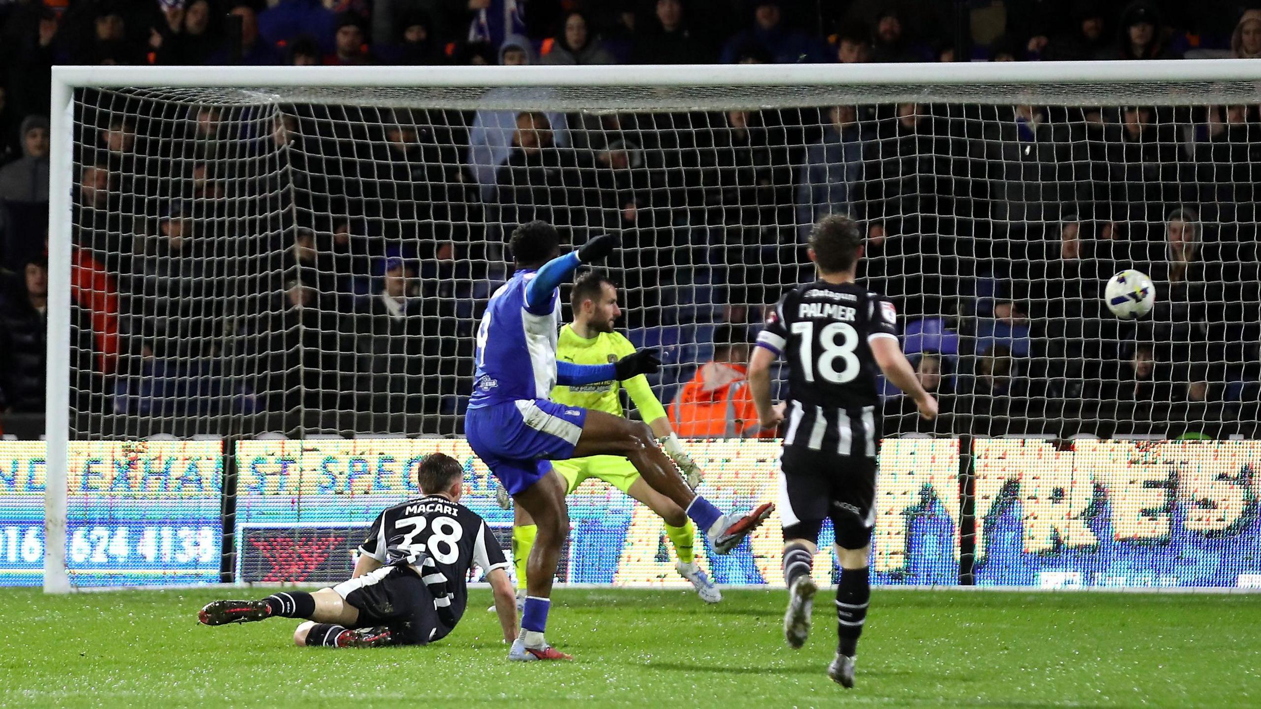 Mike Fondop holds his right leg in the air as the ball flies into the goal net