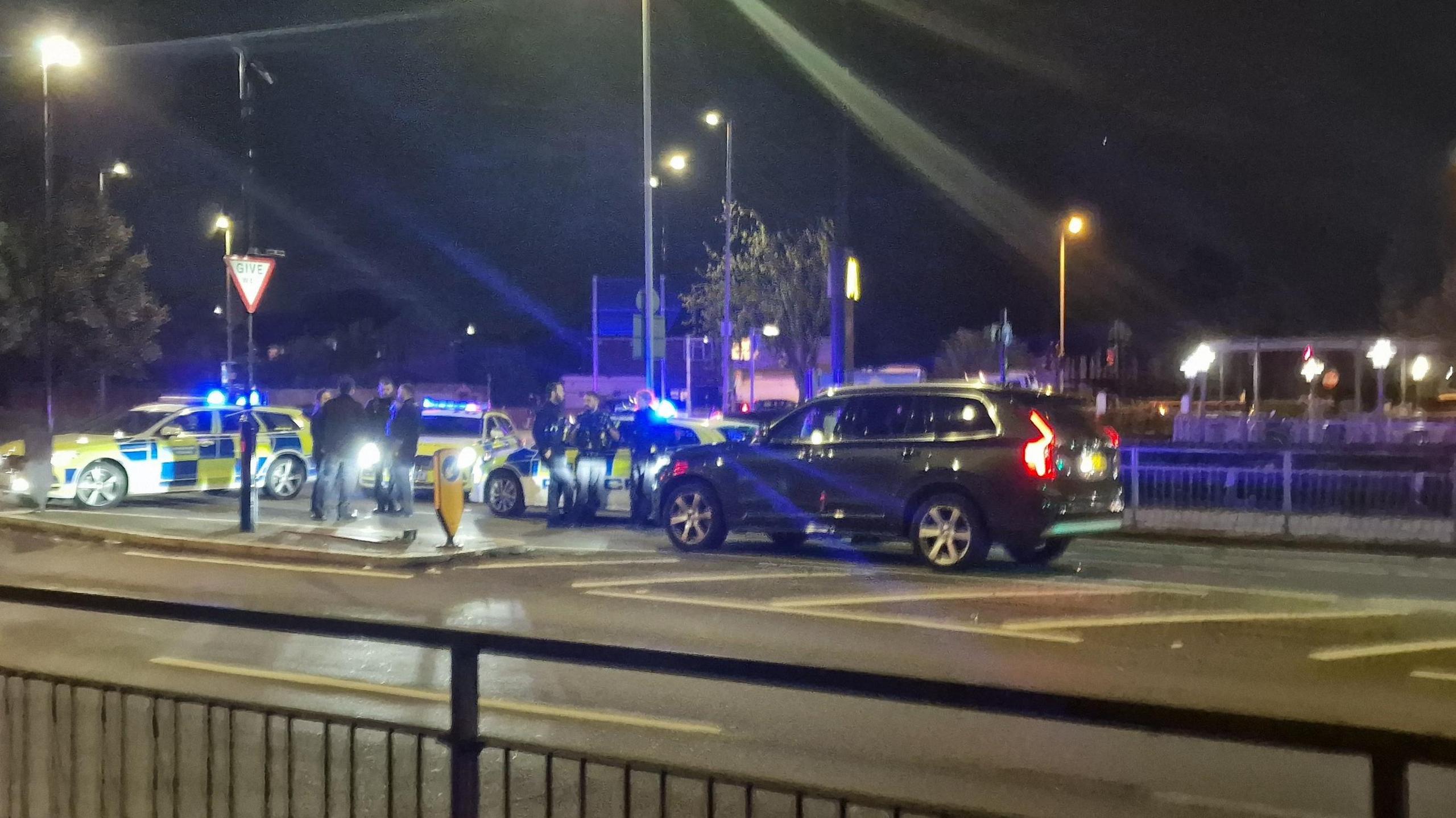 Several patrol cars and a black estate car at the crash scene 