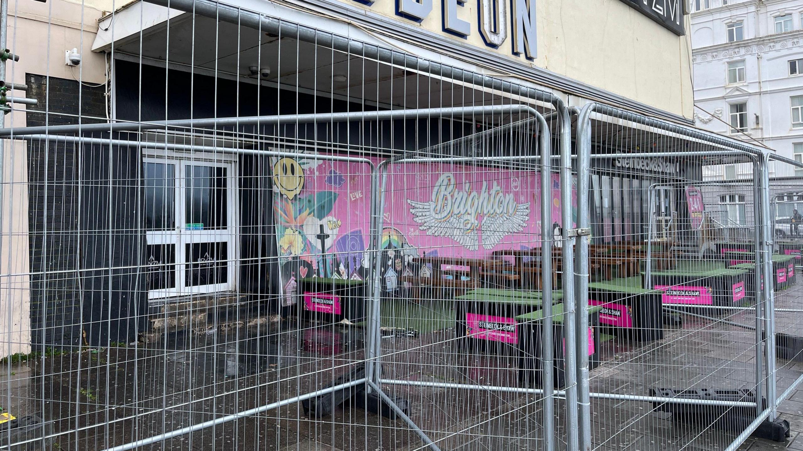 Metal work fencing around outdoor seating in front of a large building