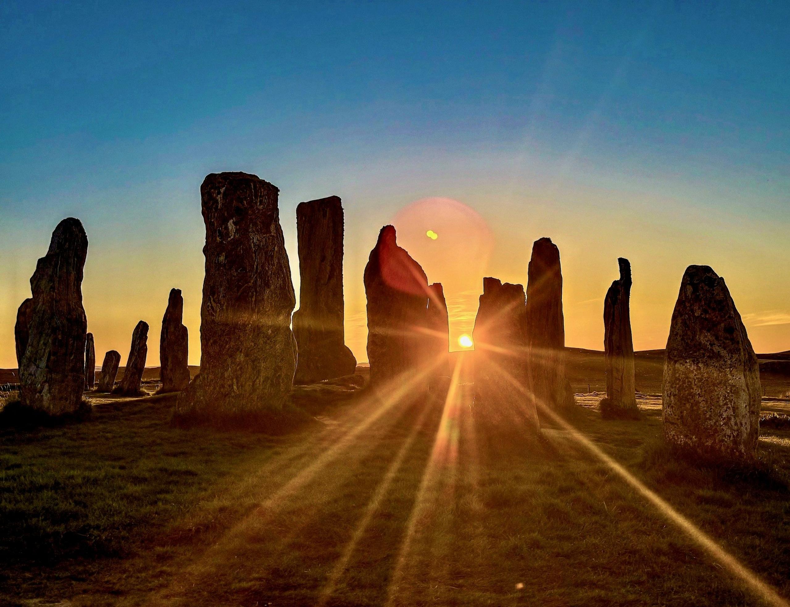 Standing stones with the sun shining through as it sets