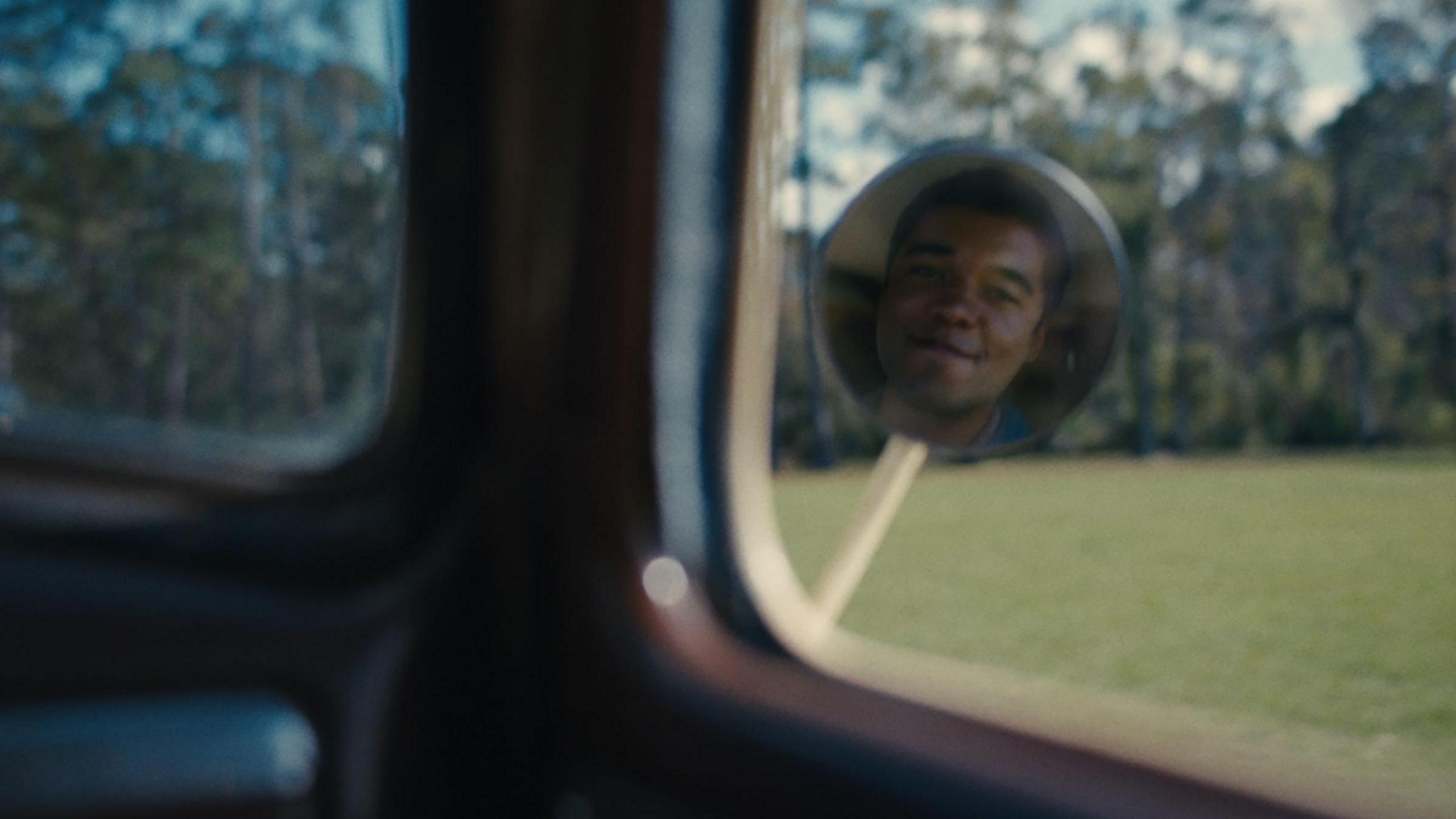 Film still from Nickel Boys showing Elwood looking at himself in a car mirror