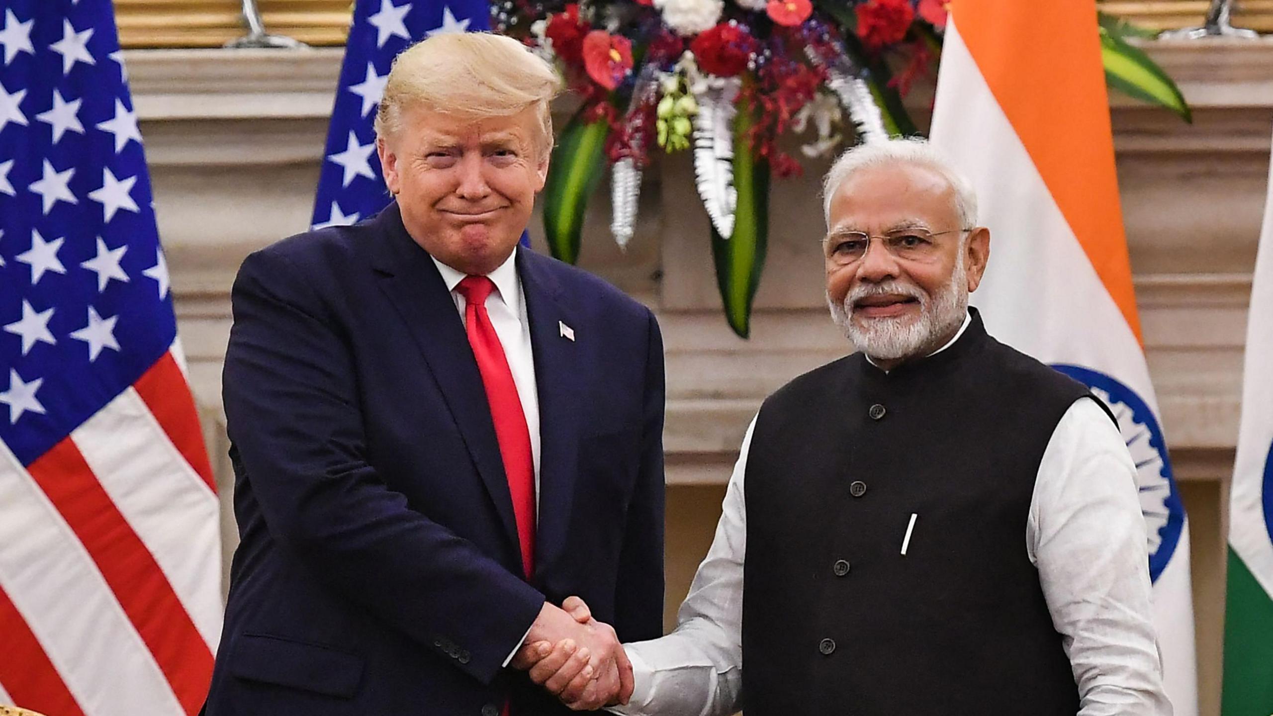 India's Prime Minister Narendra Modi (R) wearing a white kurta, a black jacket and glasses shakes hands with US President Donald Trump, who is wearing a blue suit with a white shirt and red tie before a meeting at Hyderabad House in New Delhi on February 25, 2020.