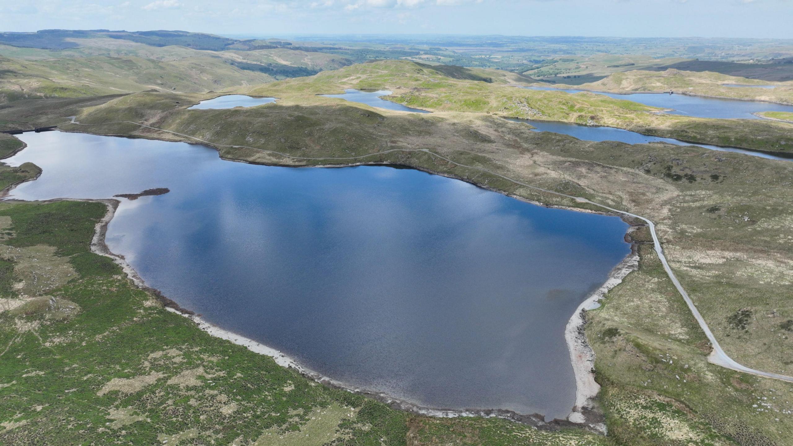 Delwedd drôn o Byllau Teifi gyda Llyn Egnant yn y blaendir.
