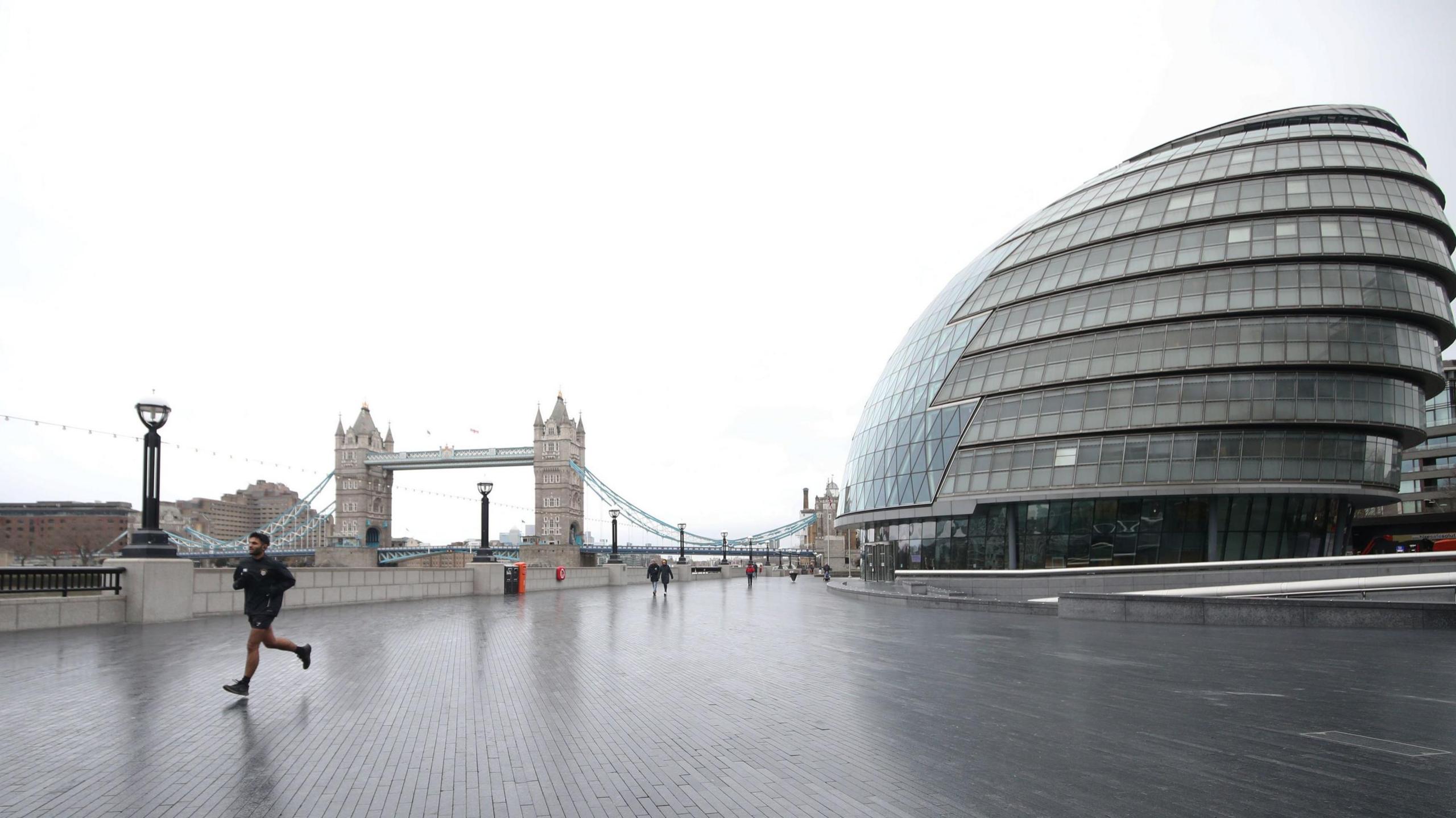 City Hall on the right of the picture and Tower Bridge on the left with a jogger in the foreground. 