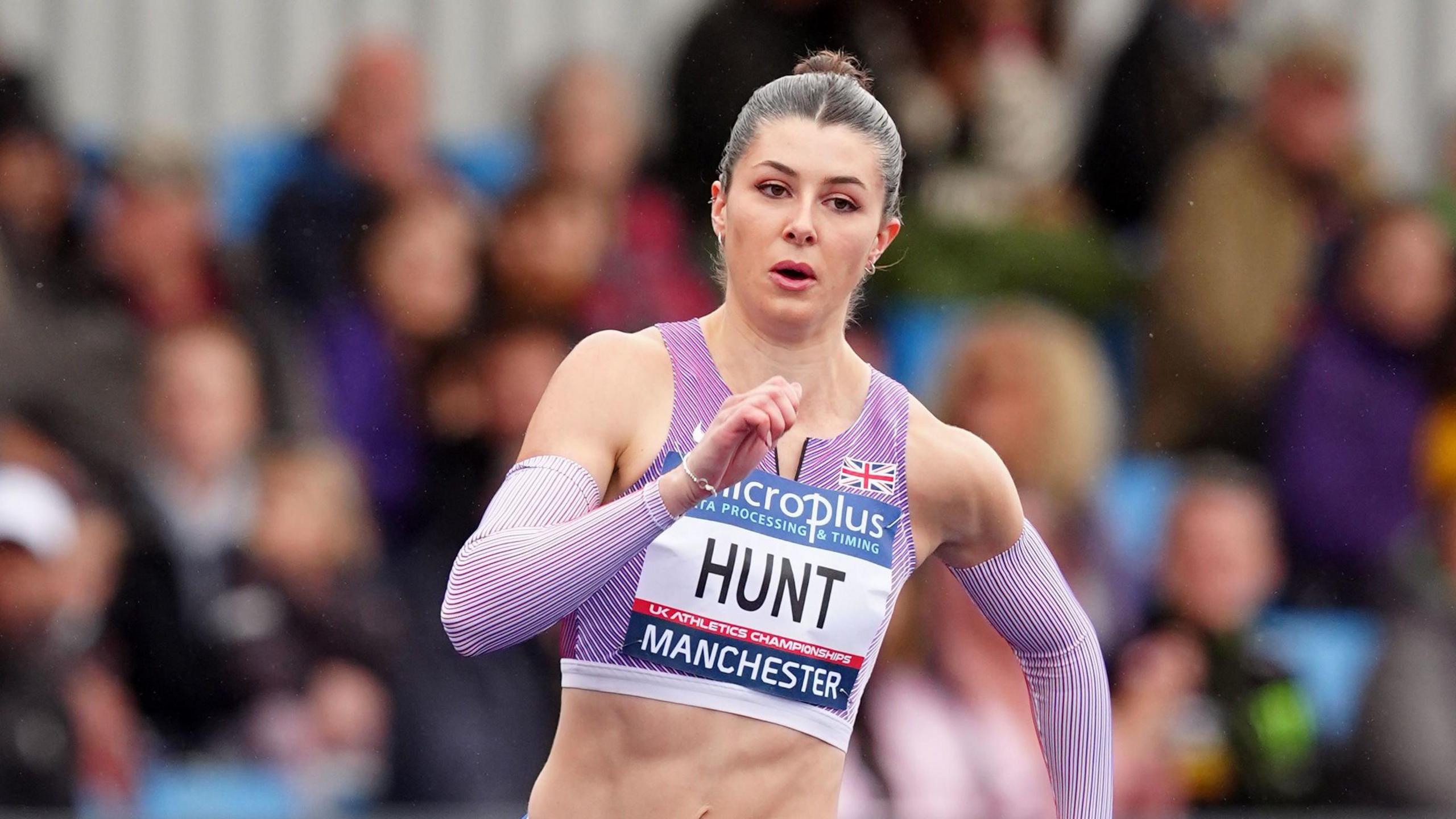 Amy Hunt sprints in the women's 200m at the UK Olympic trials. She is wearing a purple crop top with matching sleeves.