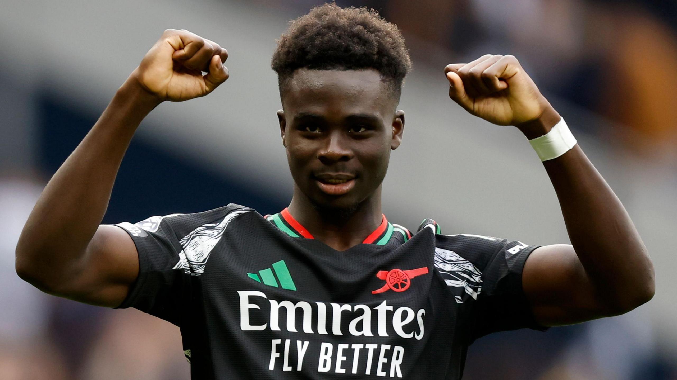 Bukayo Saka celebrating after Arsenal win against rivals Tottenham raises both hands above his head.