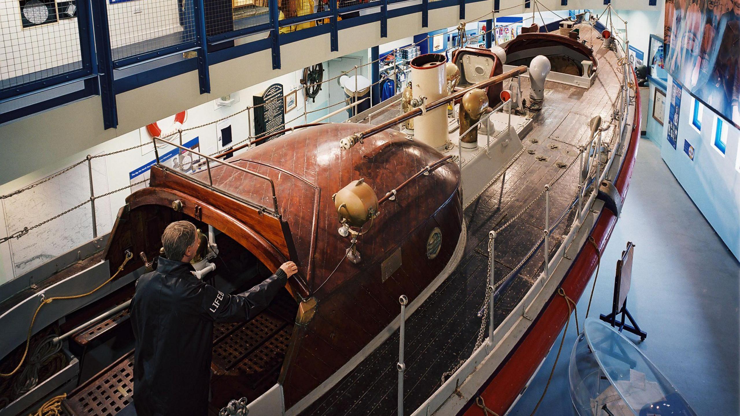 The inside of the Henry Blogg RNLI Museum, showing the old boat used by Henry Blogg with a model coxswain on board.