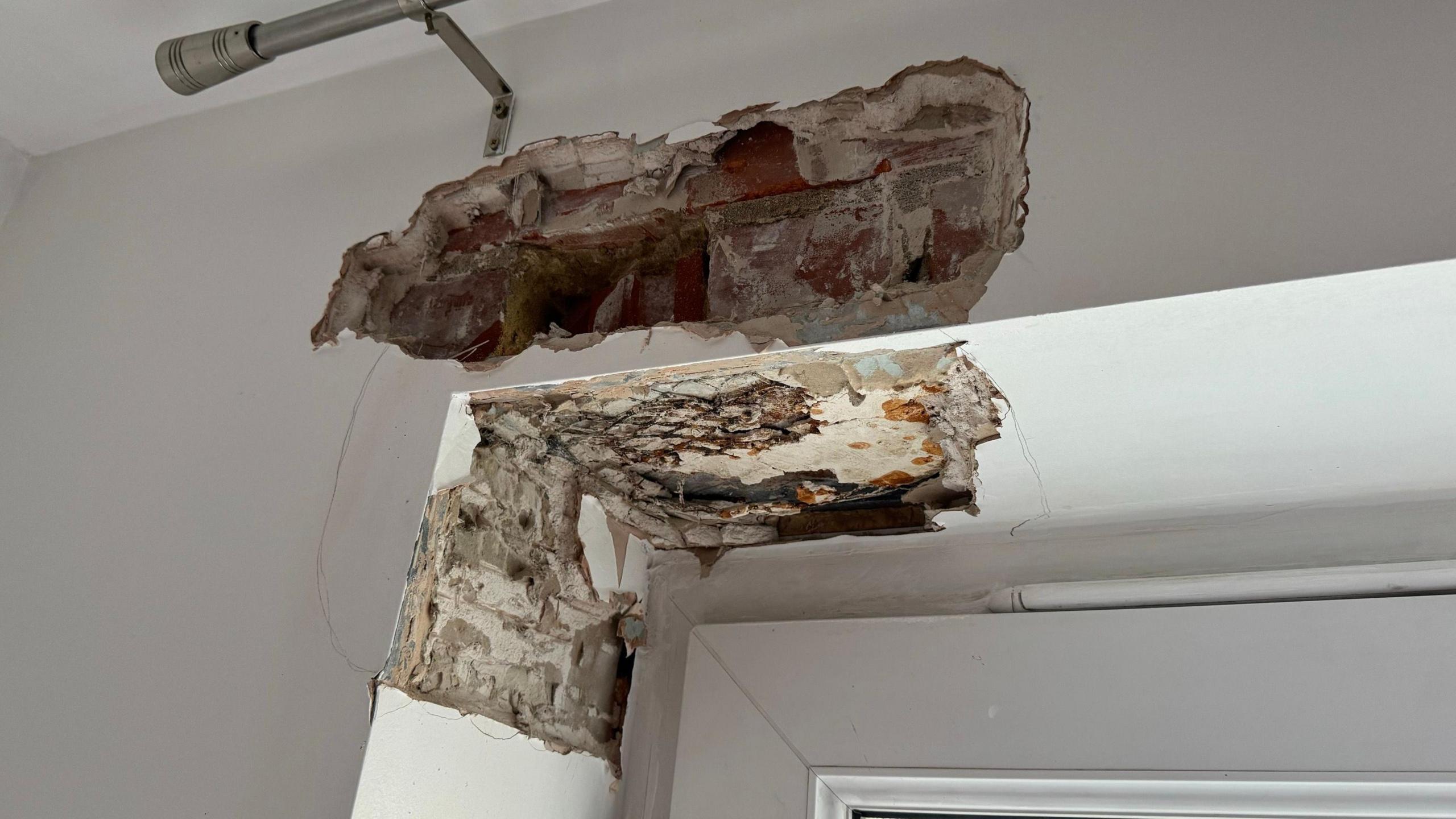 Damage on a corner of a door frame which is leaving some brick exposed.