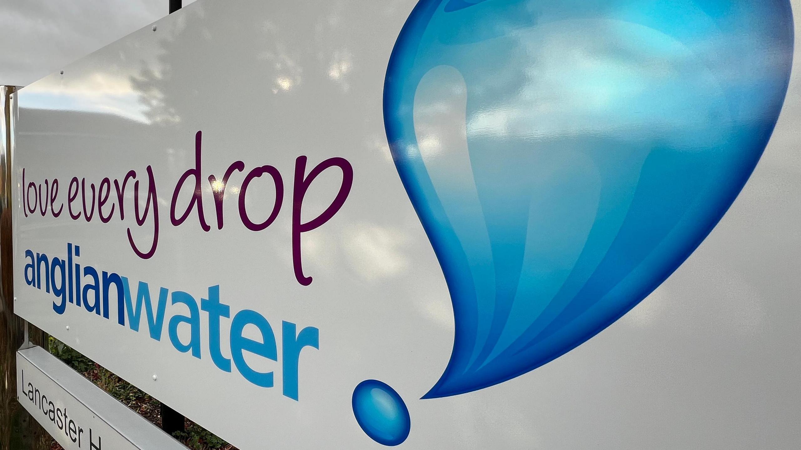 A white Anglian Water sign outside its offices. The sign says 'love every drop' with the Anglian Water logo and a blue water droplet.