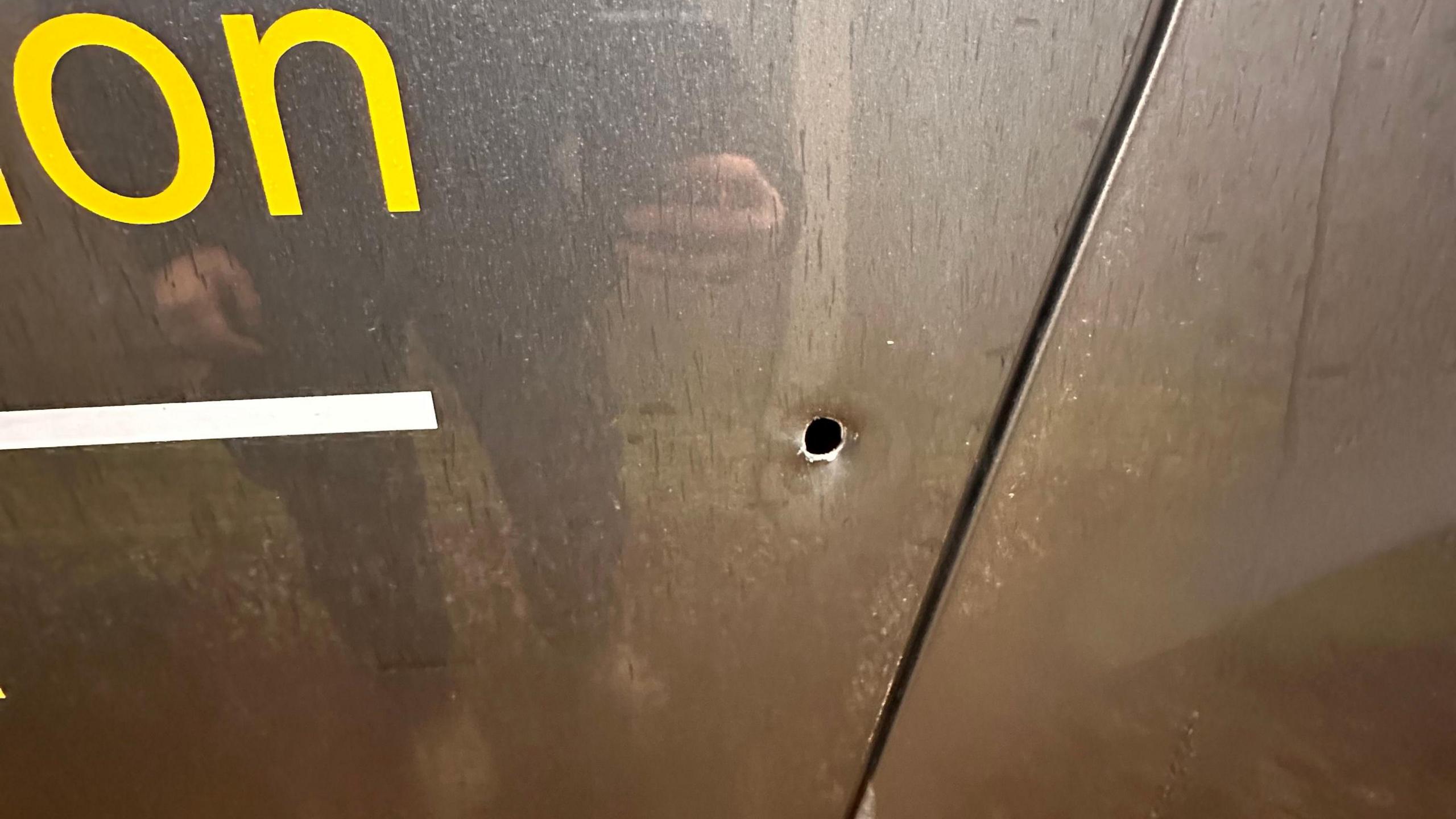 A small 2cm hole in the side of a silver van door. 