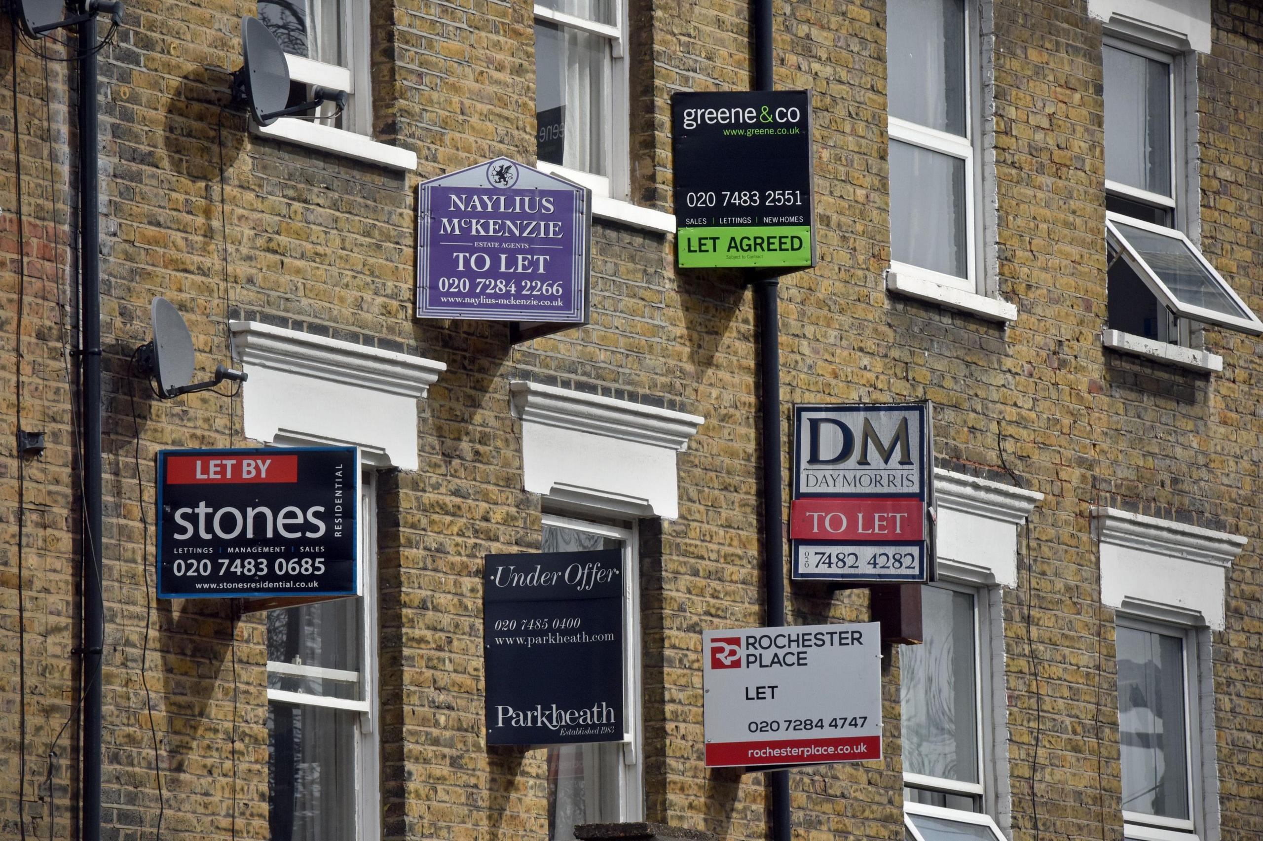 "To Let" signs attached to the wall of light brick coloured terraced homes and period feature windows.