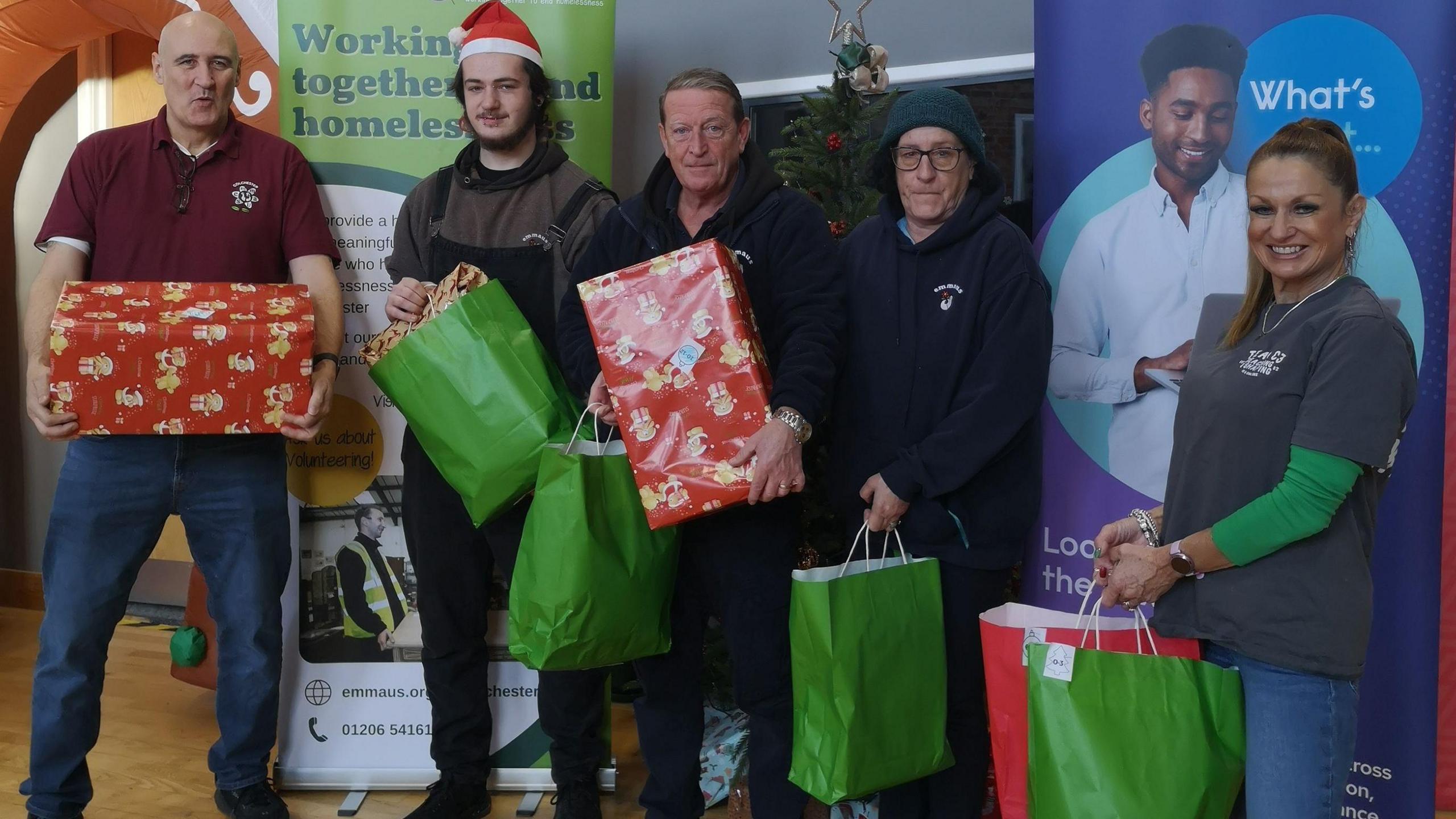 Brian Cook (CEO of Emmaus), Genesis Smith from Emmaus , Darren Scott (business manager of Emmaus), Denise from Emmaus and Ella Havell from The C3 Church gave out gifts standing in front of a tree holding gifts