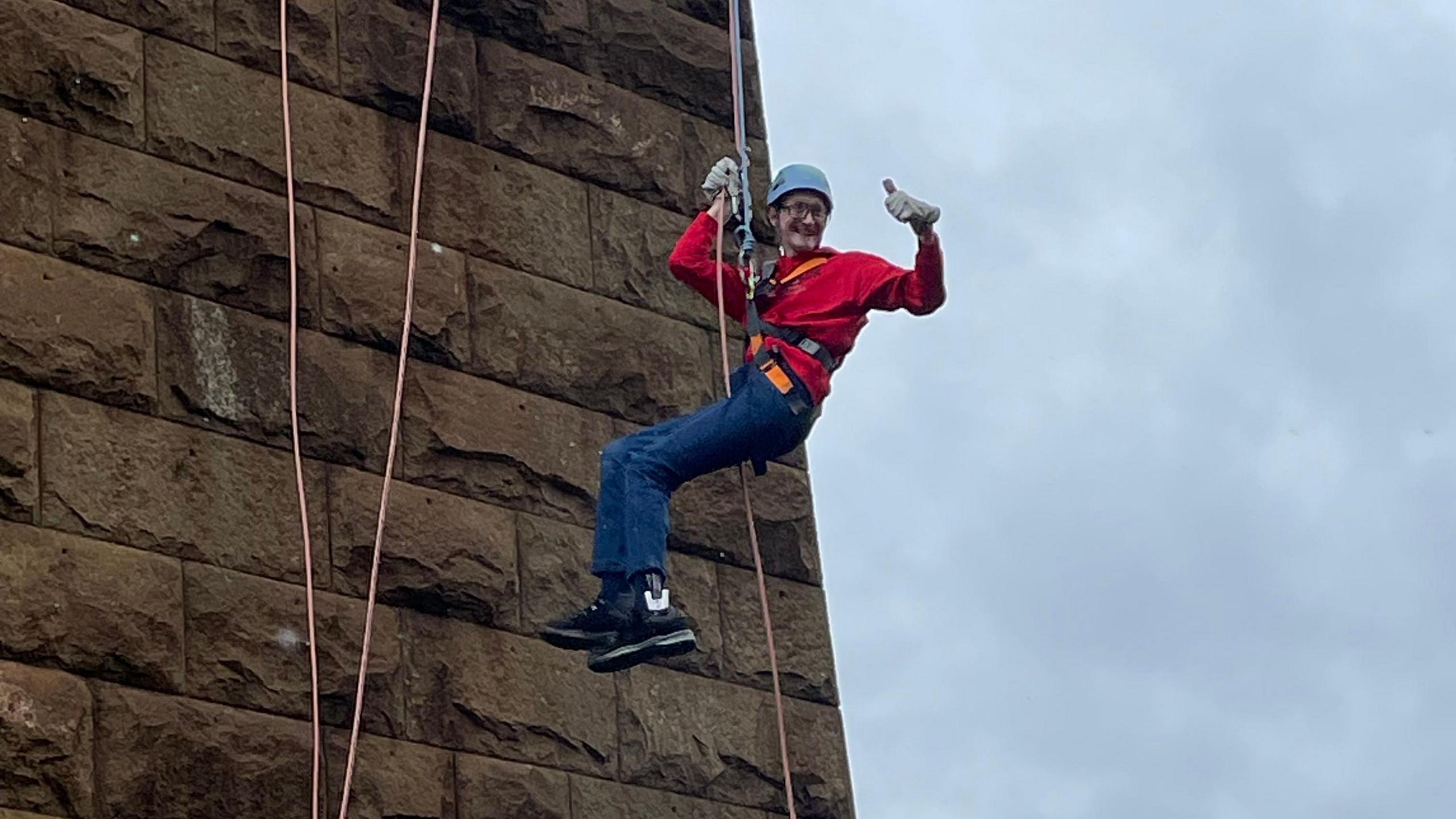 Josh abseiling down the bridge and giving a thumbs up