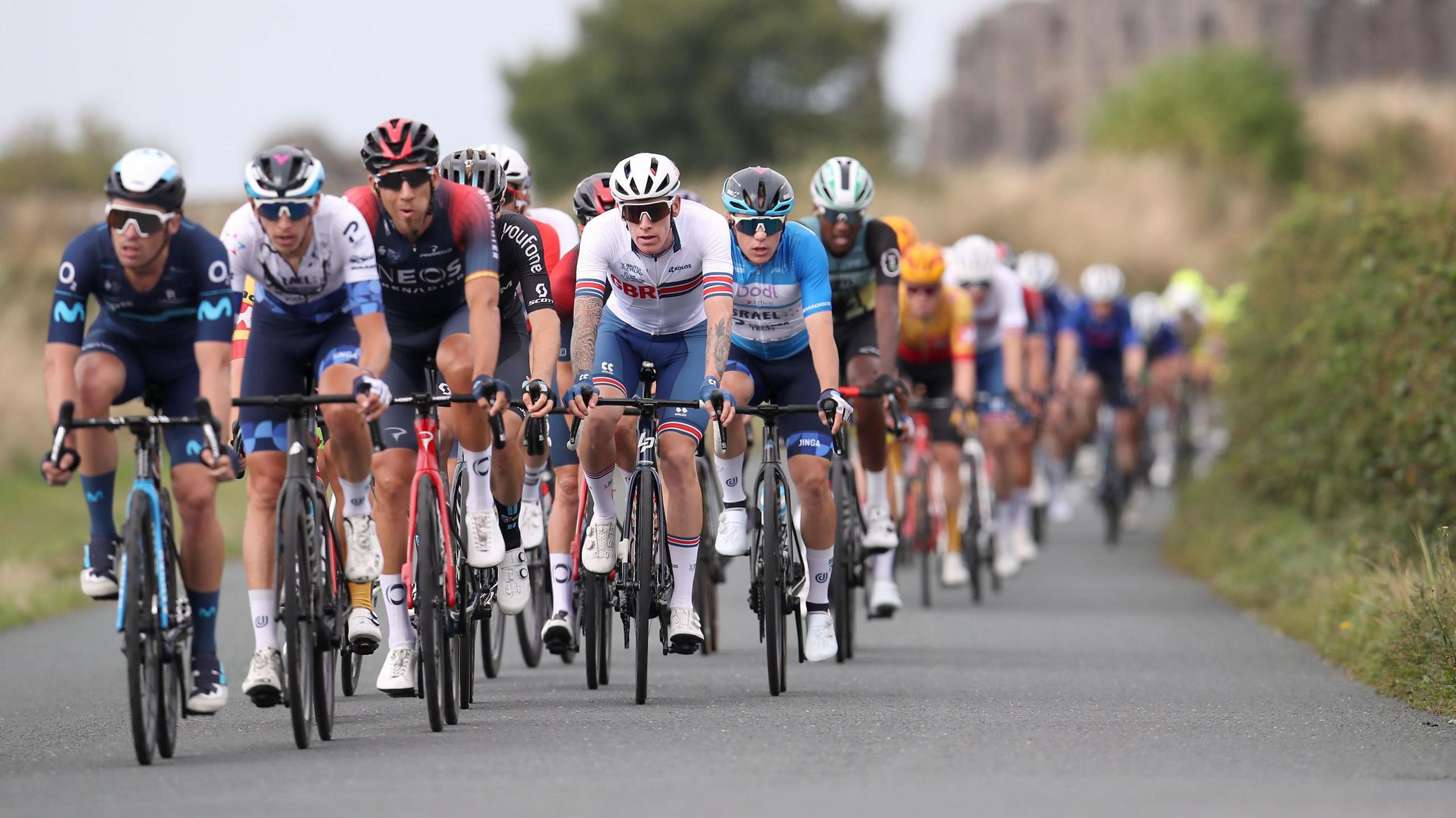 A line of cyclists riding down a road 