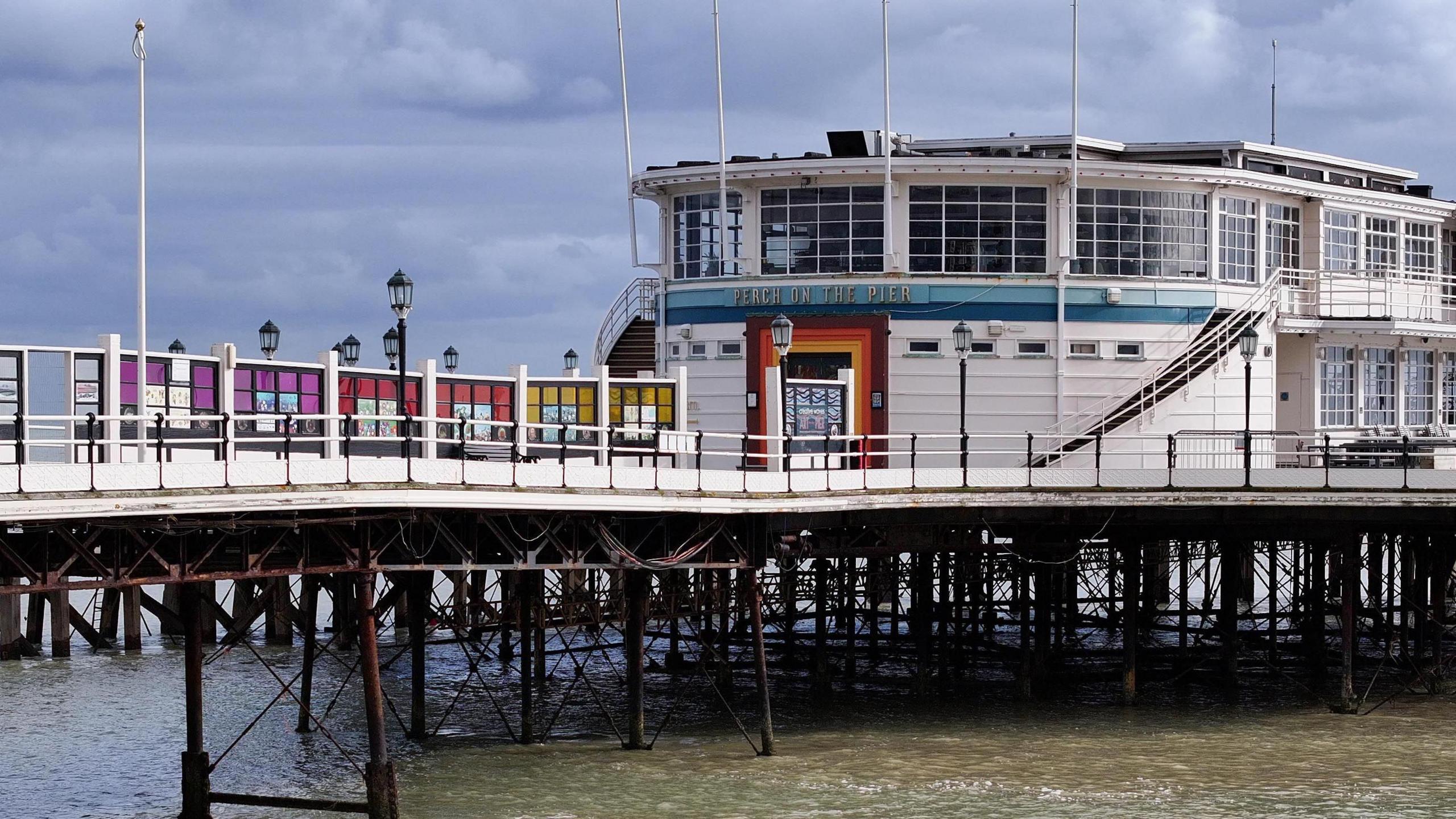 A whilte pier and building with dark metal supports underneath