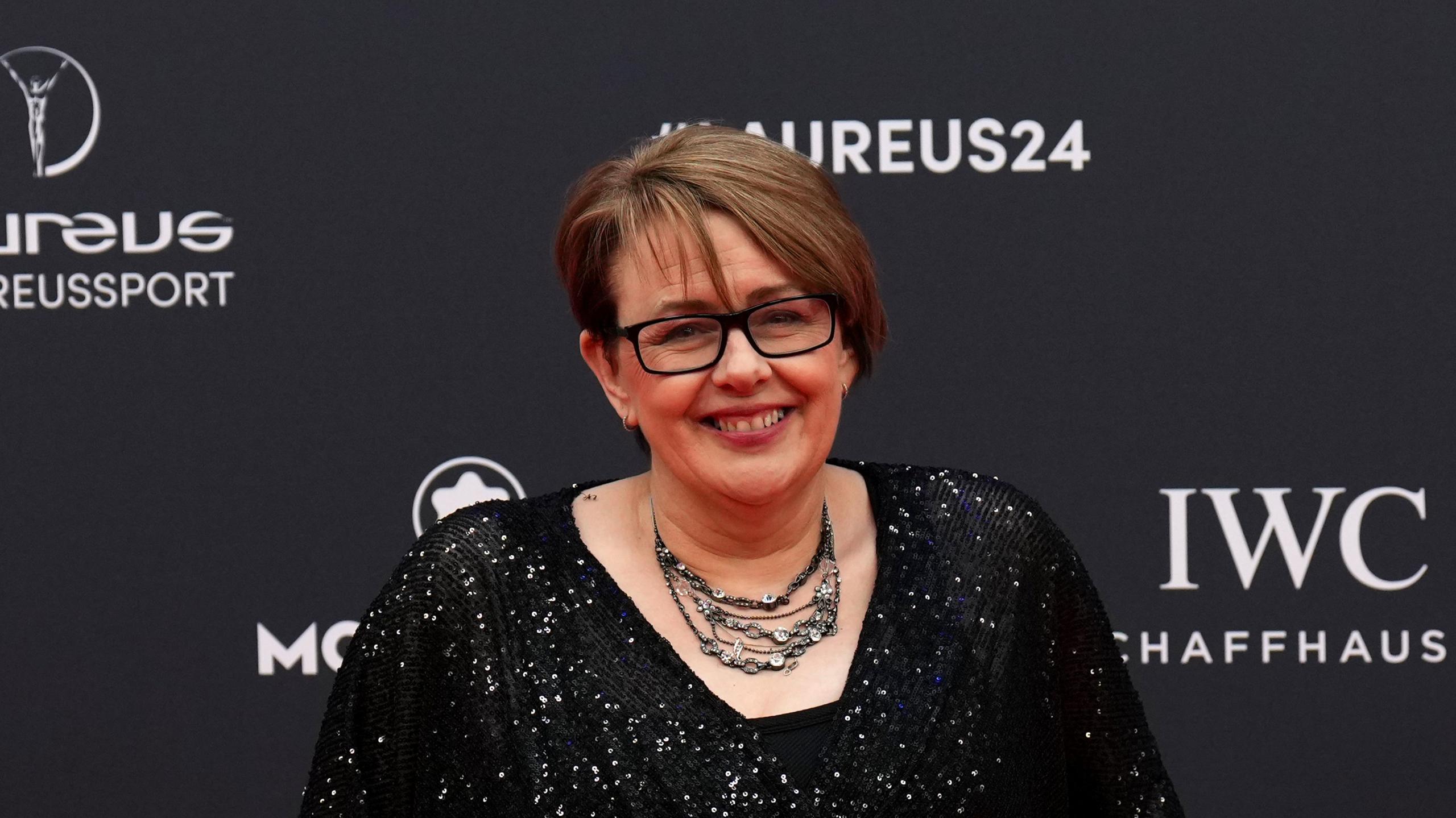 Tanni Grey-Thompson at the 2024 Laureus World Sports Award  in Madrid, she is smiling for the camera and wearing a black dress with sequins, a necklace and black-rimmed glasses