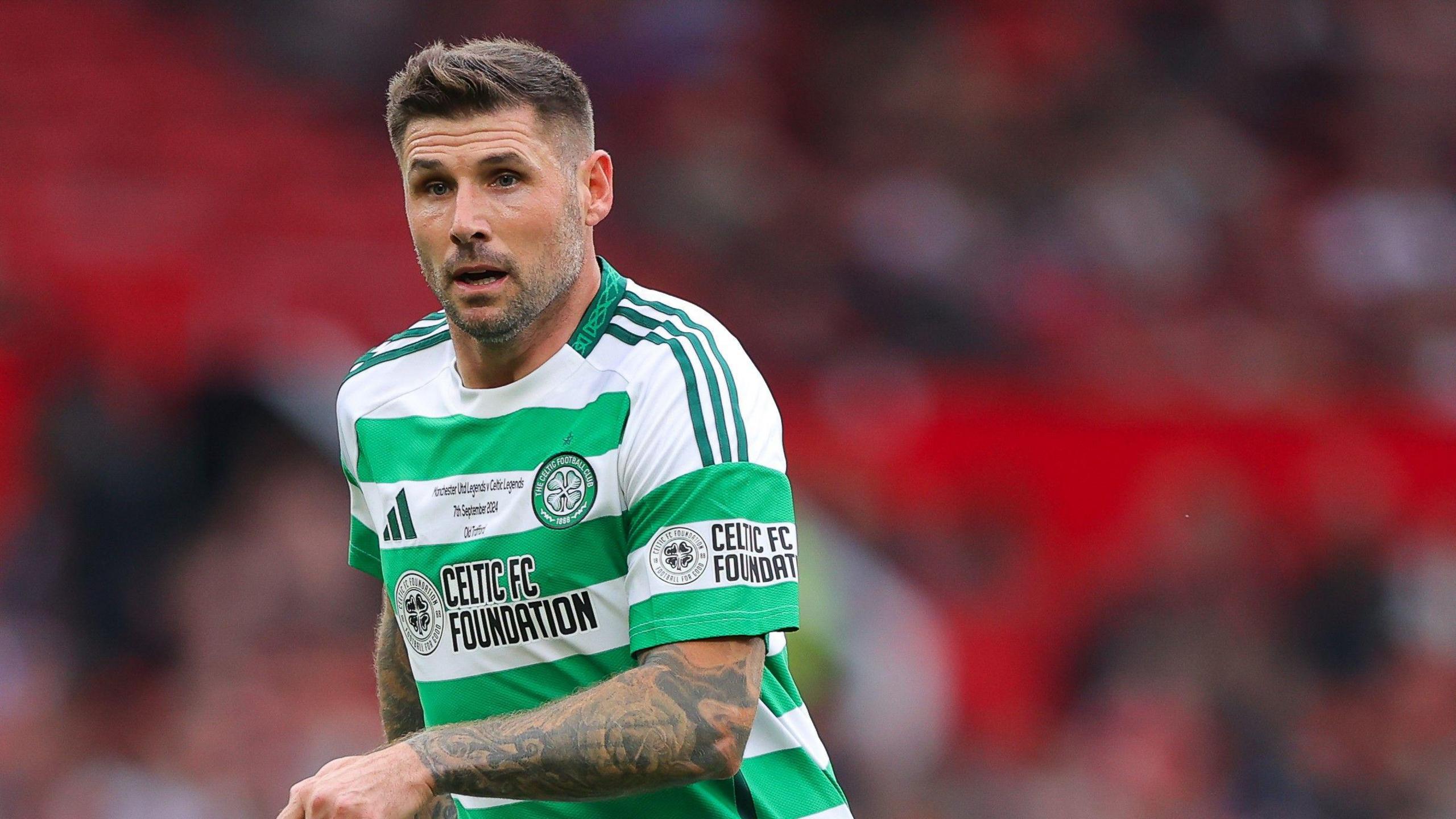 Gary Hooper with short hair brown hair and stubble, running in a Celtic white and green hooped top.