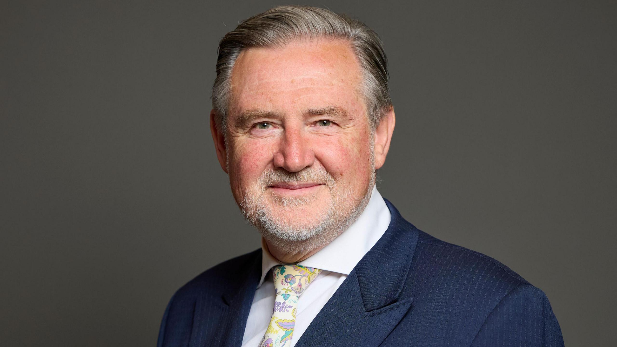 Barry Gardiner's official MP portrait. He wears a navy suit and floral tie. 