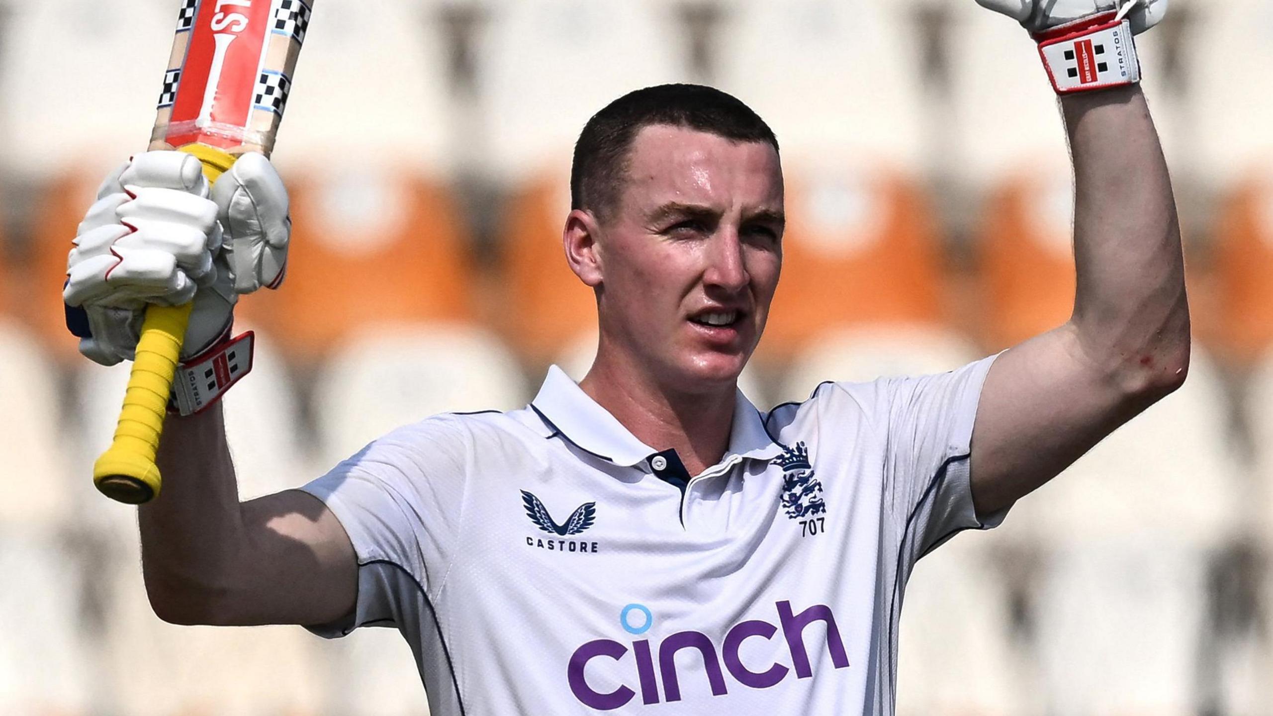 Harry Brook lifts his bat and helmet, the latter out of shot, after reaching 300 in Multan
