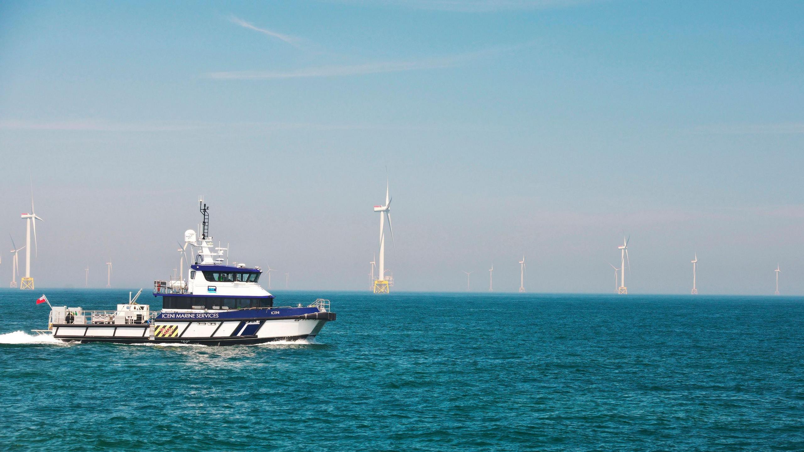 A wind farm service vessel in the north sea, with turbines in the background