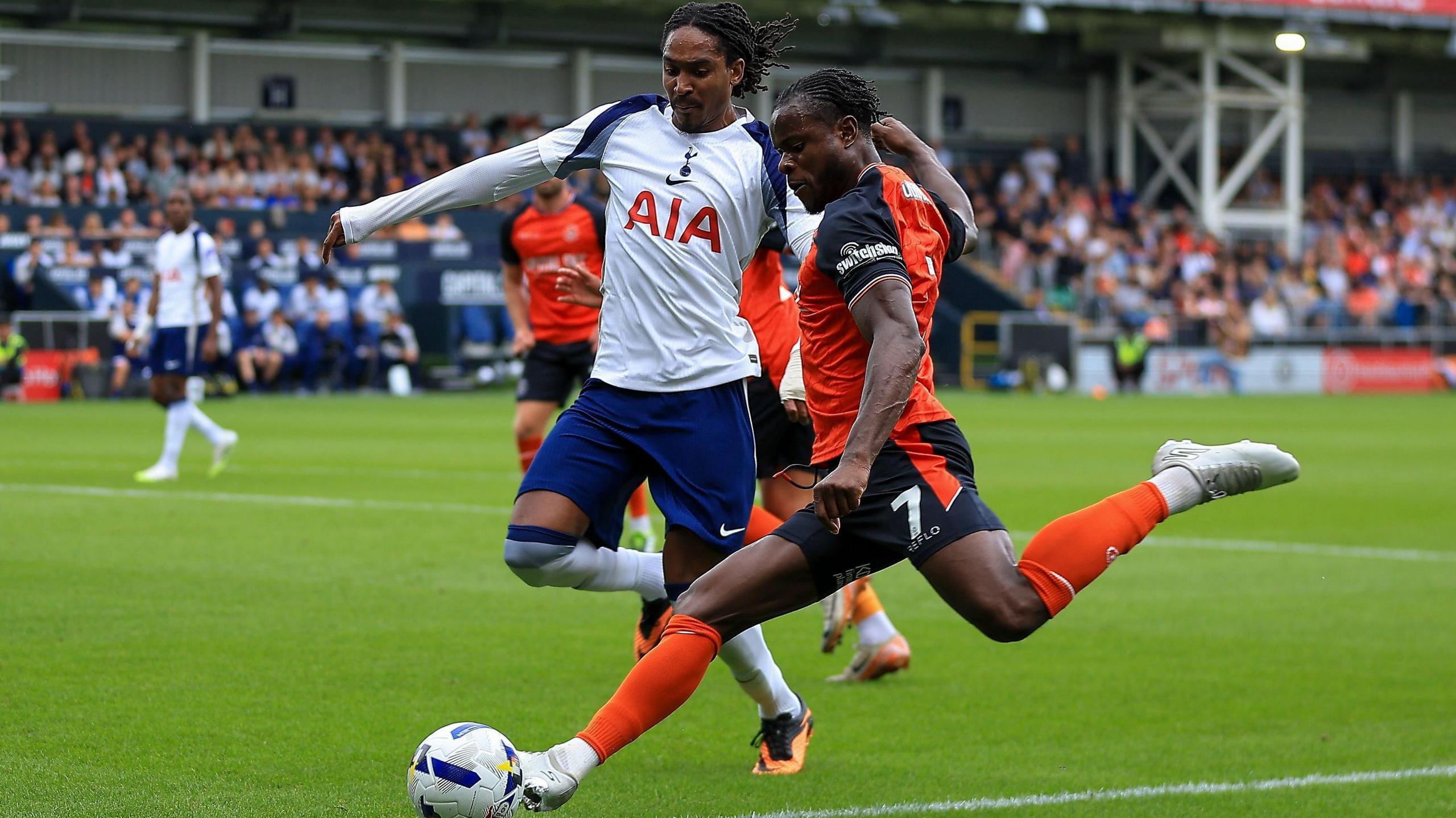 Luton forward Millenic Alli sends in a cross under press from Tottenham's Djed Spence