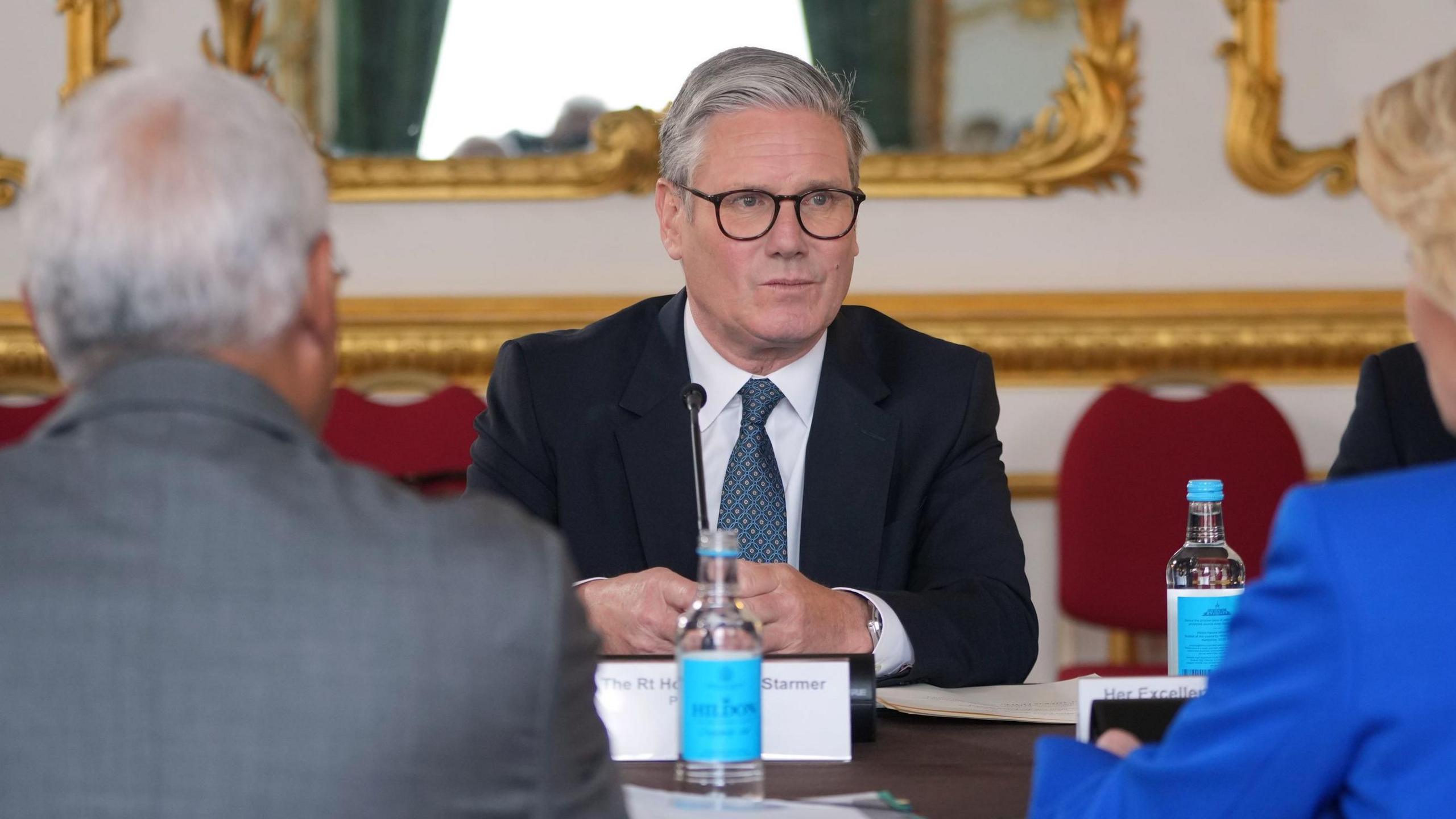 Sir Keir Starmer sitting at a table in Lancaster House, opposite European Commission President Ursula von der Leyen and European Council President Antonio Costa, who have their back to the camera.