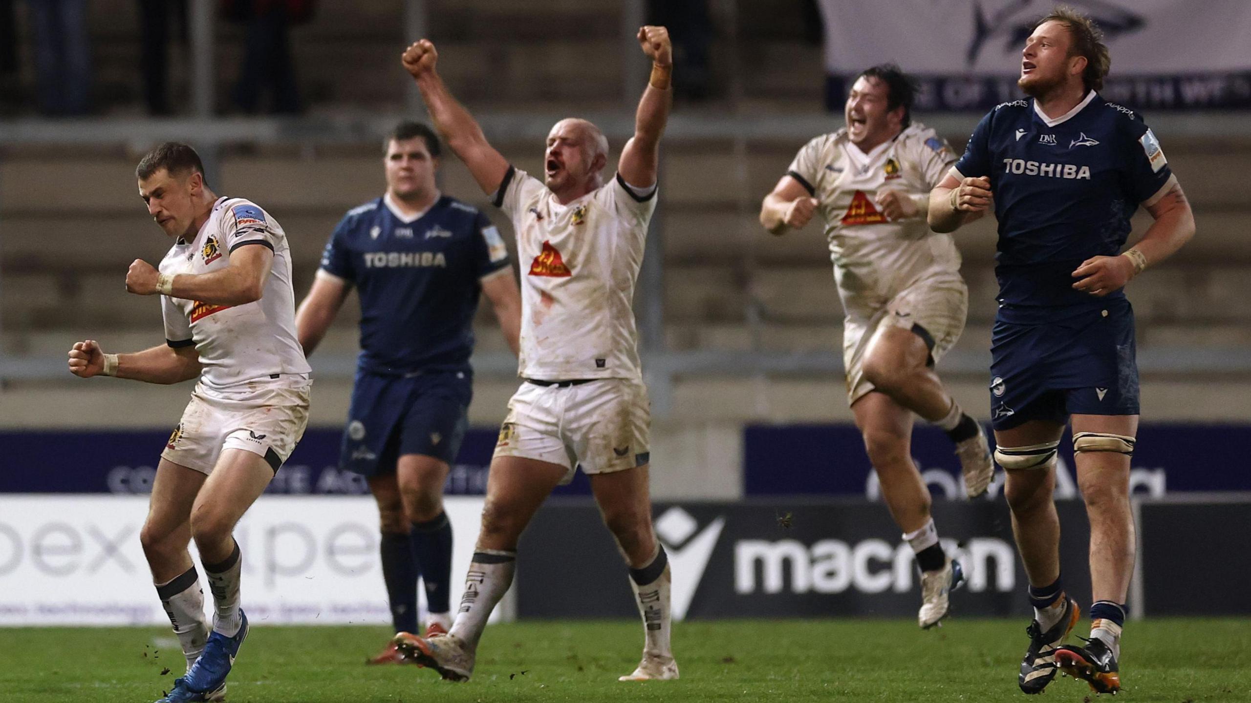Three Exeter players celebrate at the final whistle while two Sale players look dejected