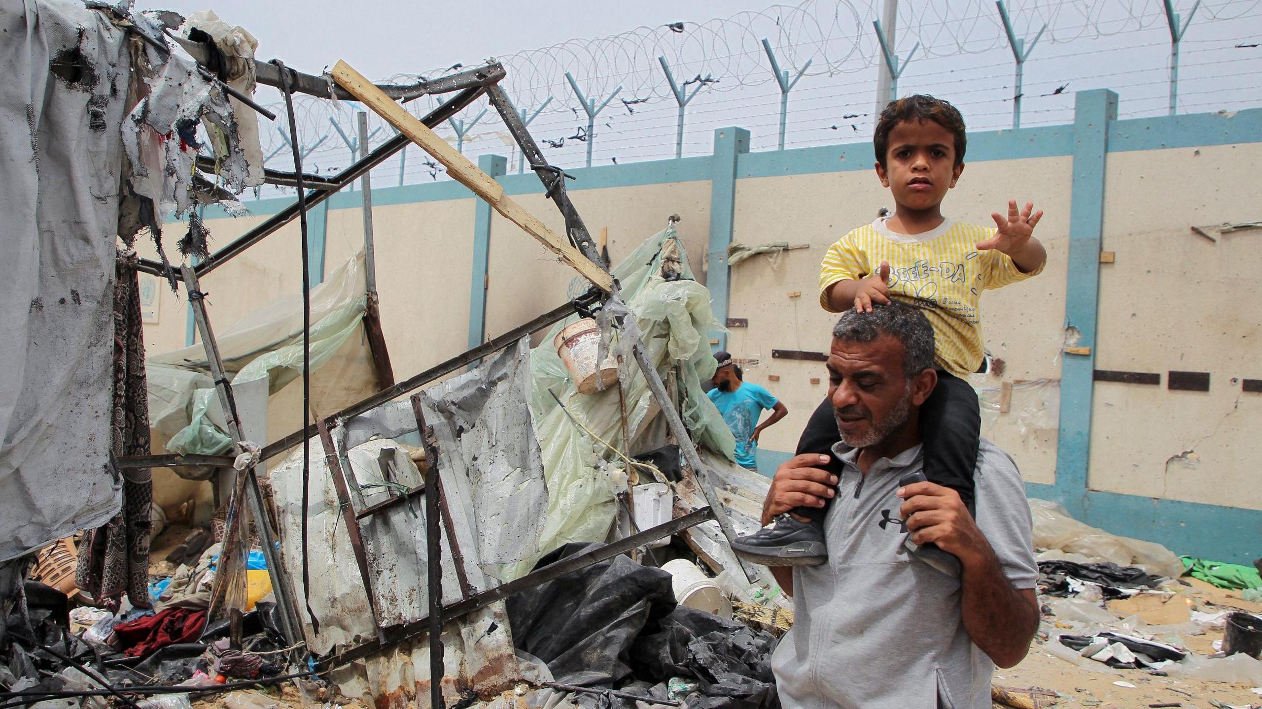 A man and a young boy walk among ruins in Rafah