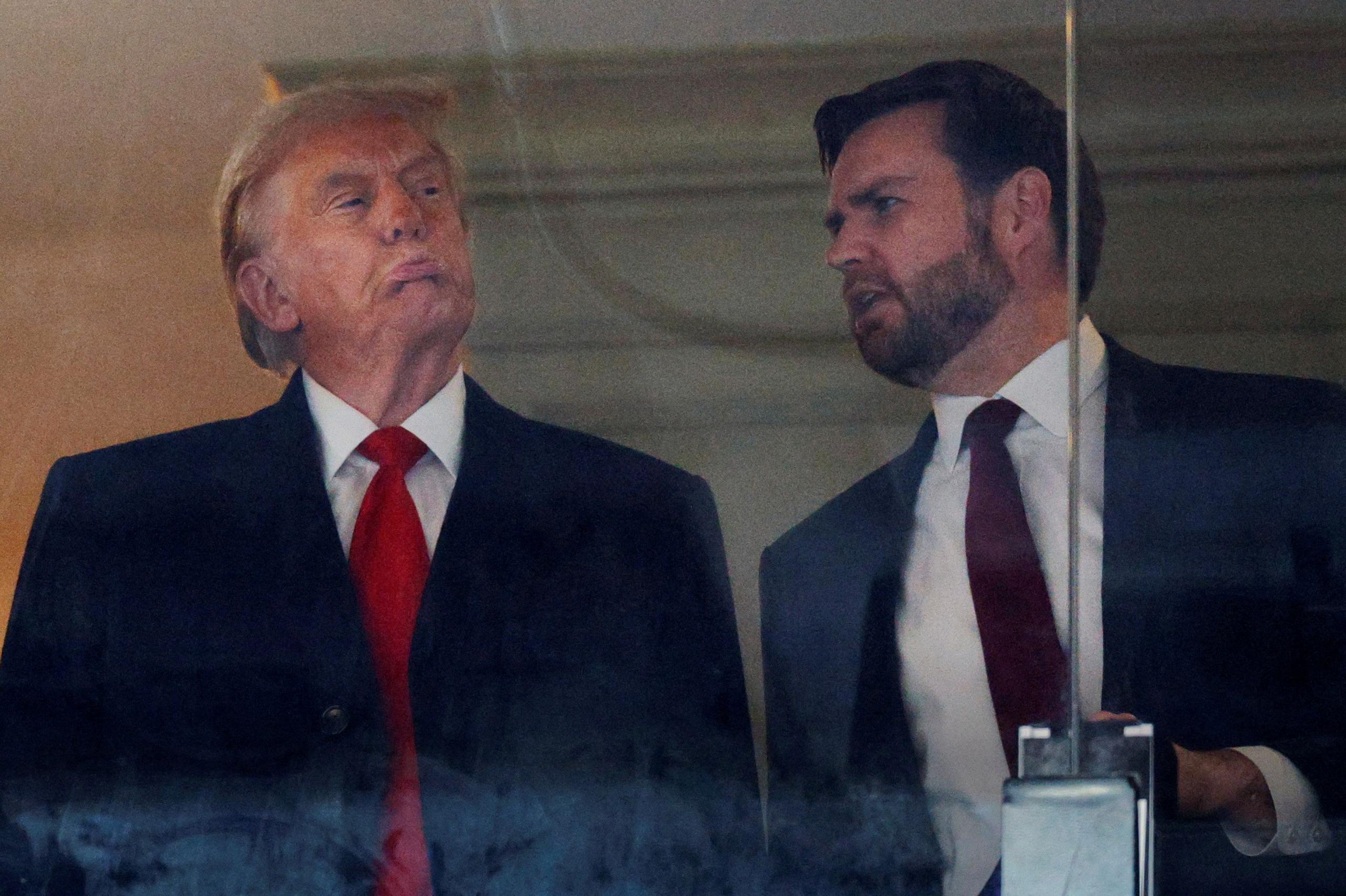 Donald Trump and JD Vance behind a glass panel, speaking to each other