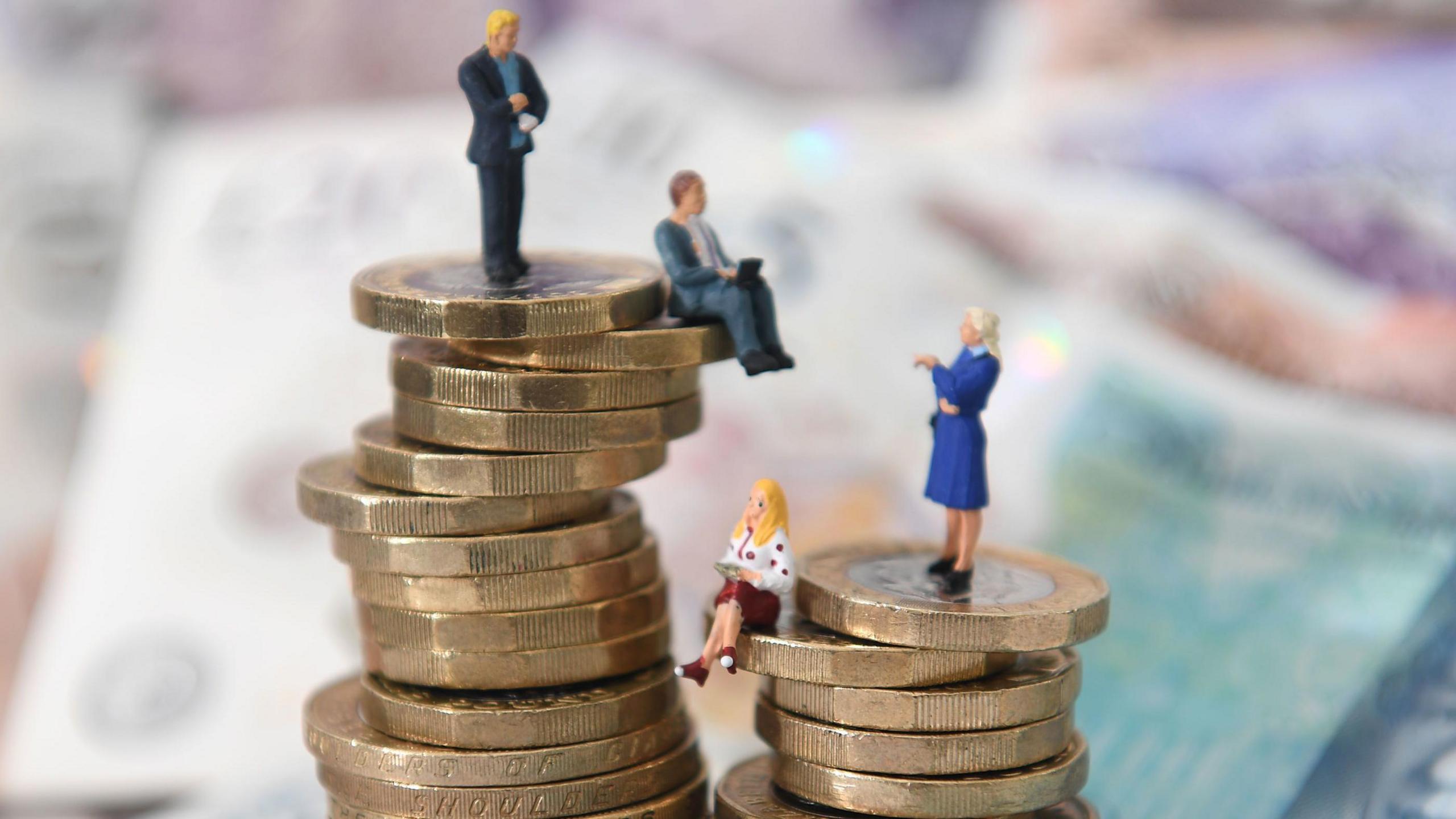 Plastic figures sitting on pound coins