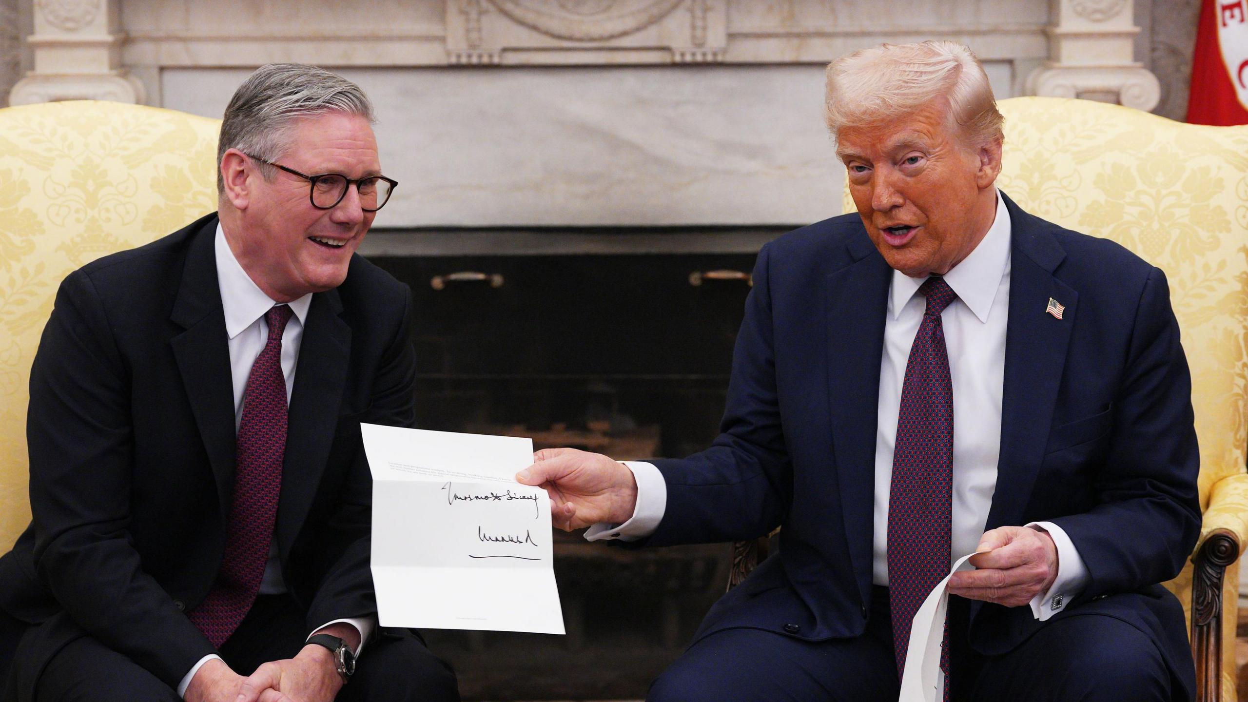 UK Prime Minister Sir Keir Starmer and US President Donald Trump seen in Oval Office holding the letter from the king