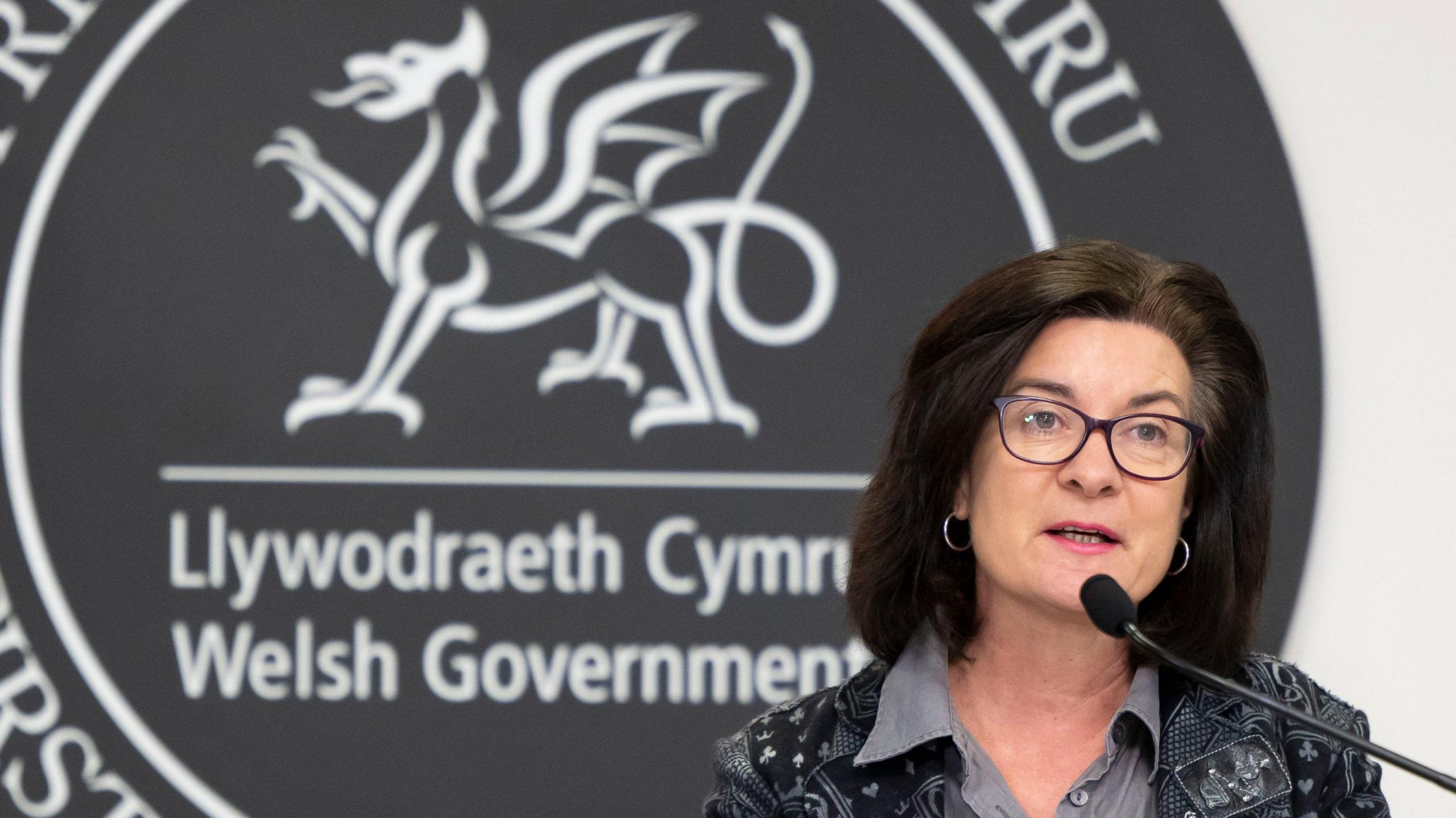 Y logo yn gefndir i gyhoeddiadau gan y Prif Weinidog Eluned Morgan