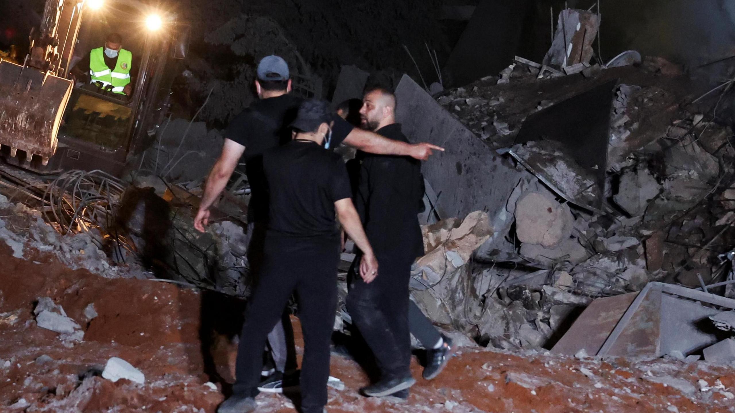 An excavator operates at the site of an Israeli strike, amid ongoing hostilities between Hezbollah and Israeli forces.