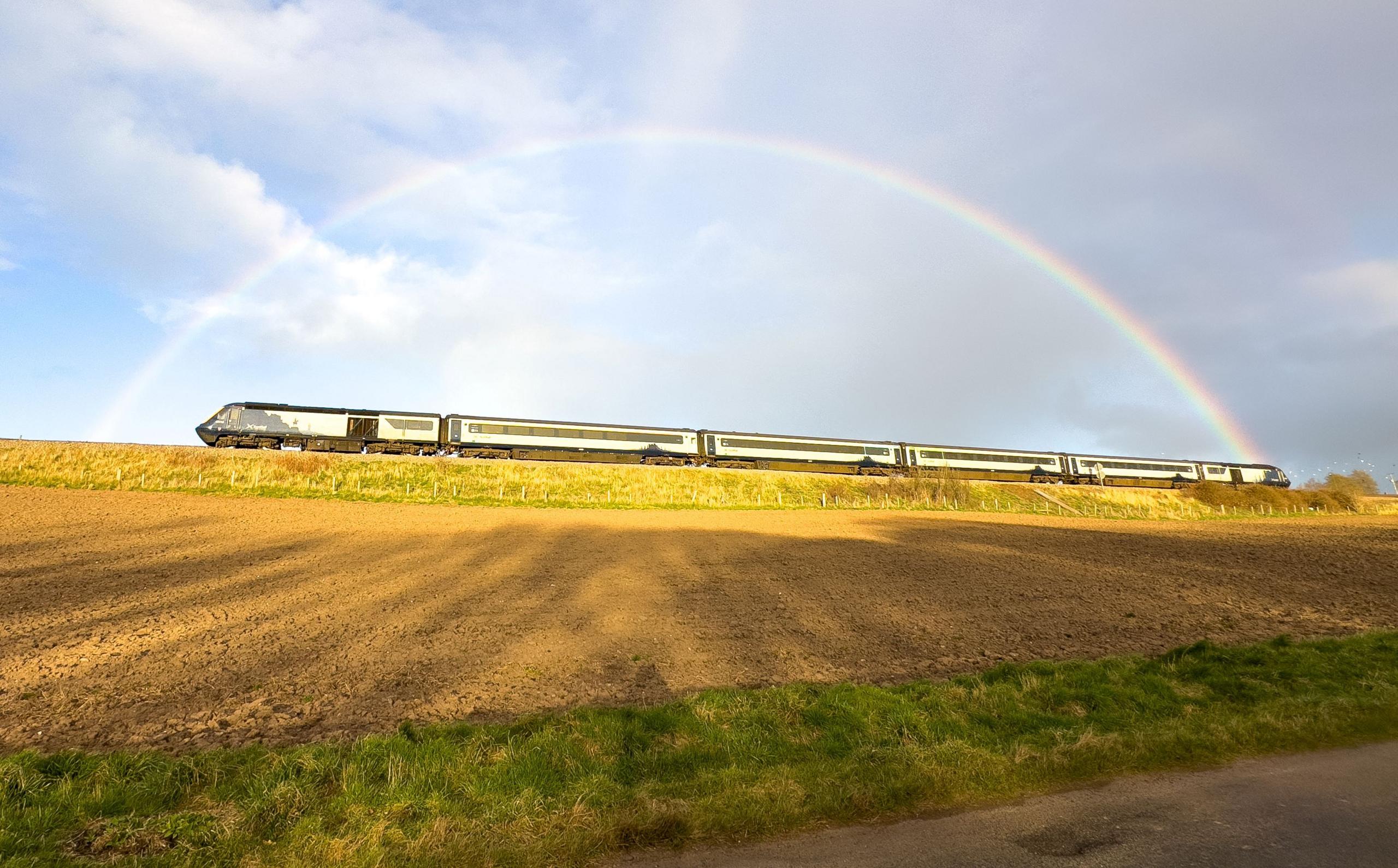 A moving train framed by a rainbow.