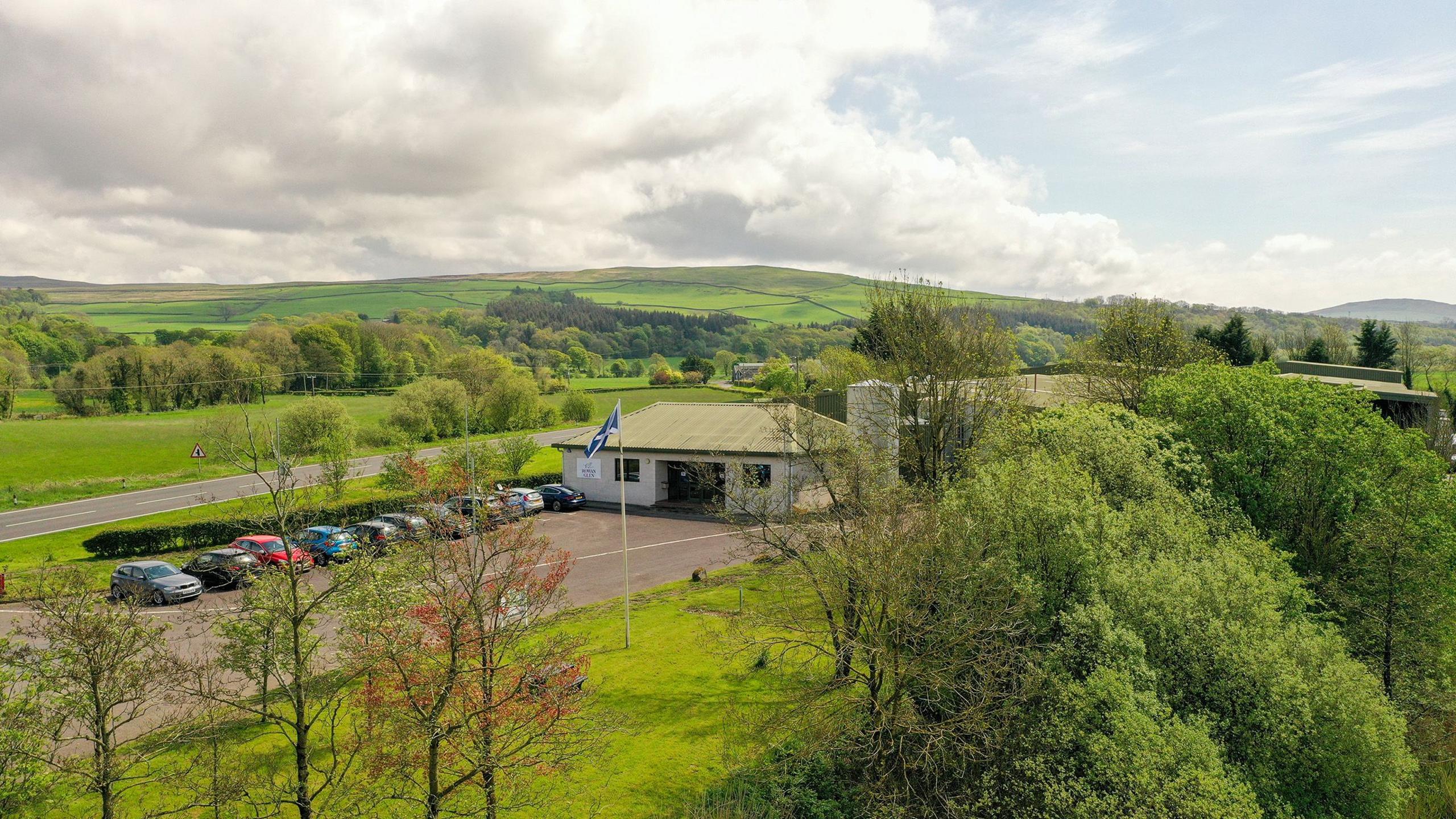 A factory building with cars parked outside in the Scottish countryside