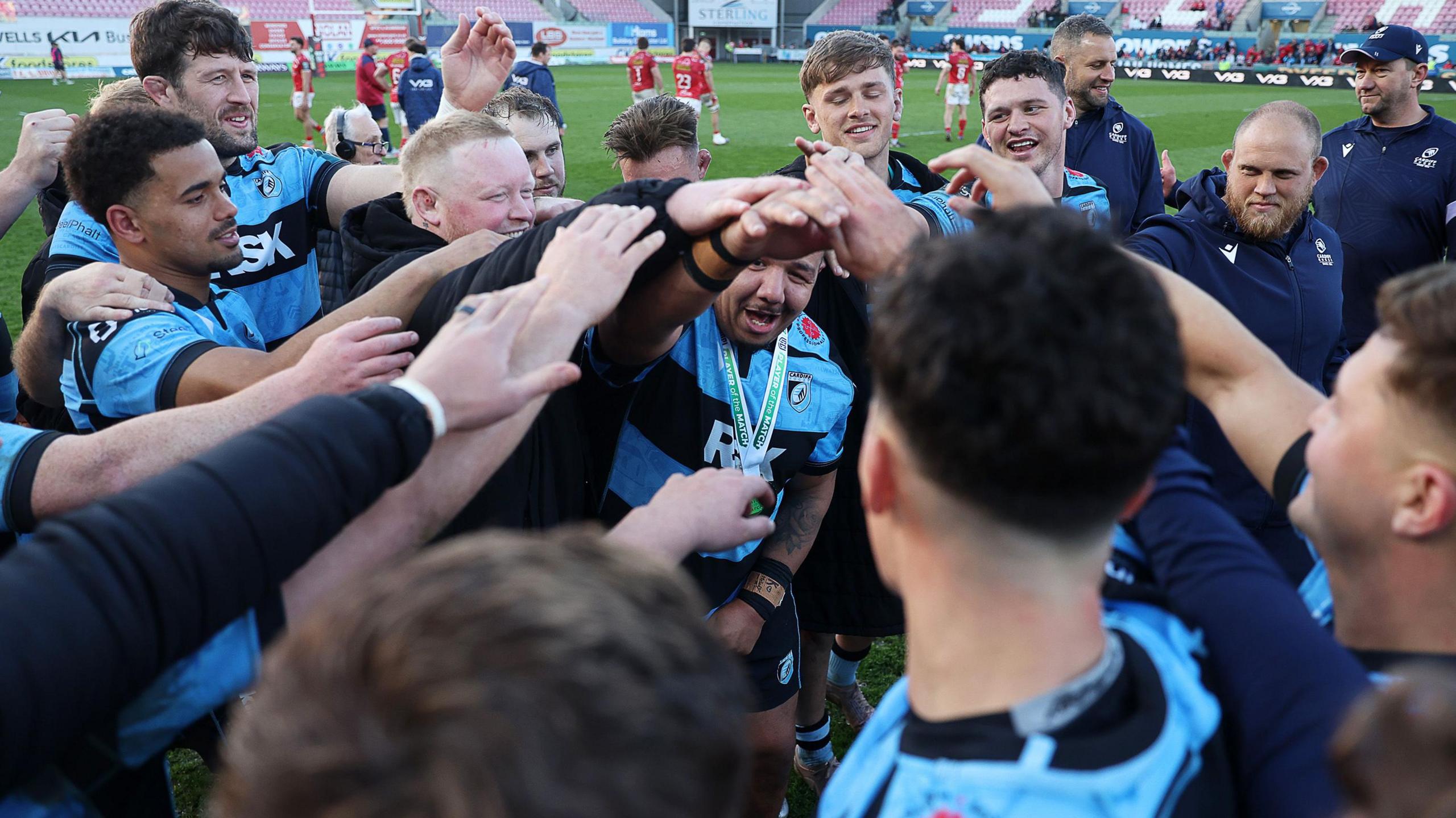 Cardiff players celebrate in a huddle after the victory against Scarlets with hands touching in the centre of the circle