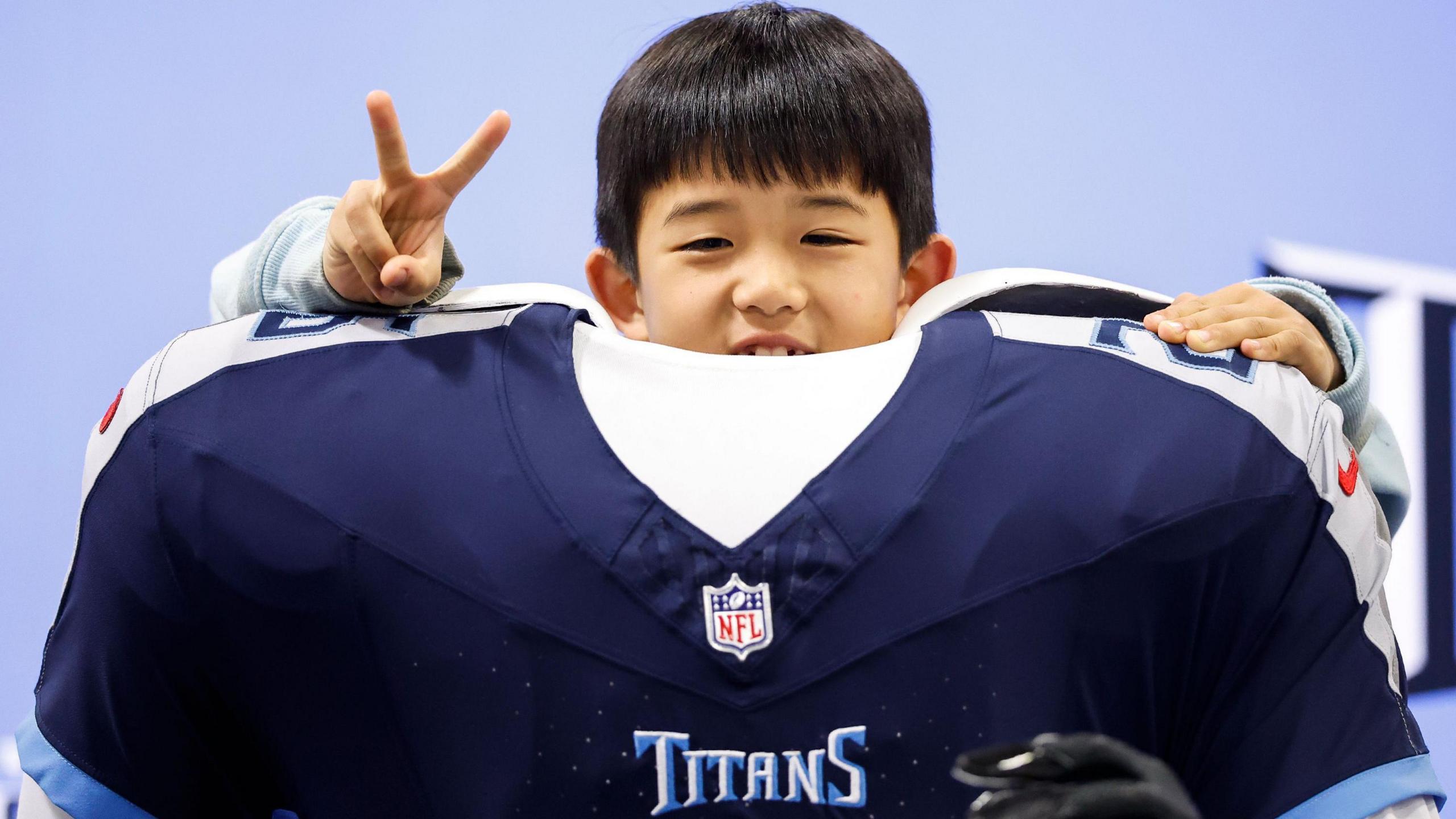 A child poses with a shirt from the New England Patriots 