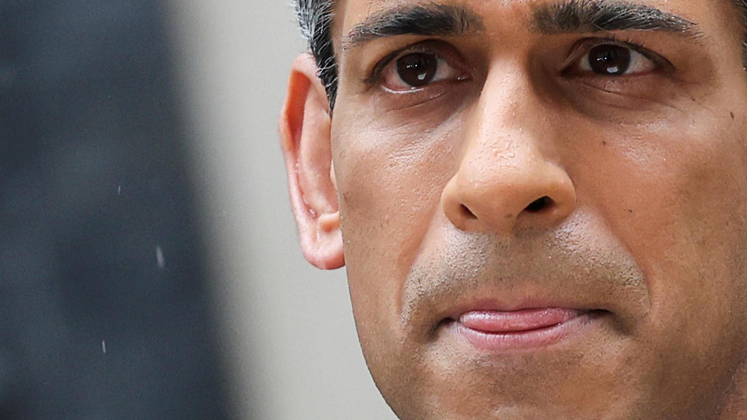 Rishi Sunak standing in the rain in front of Downing Street