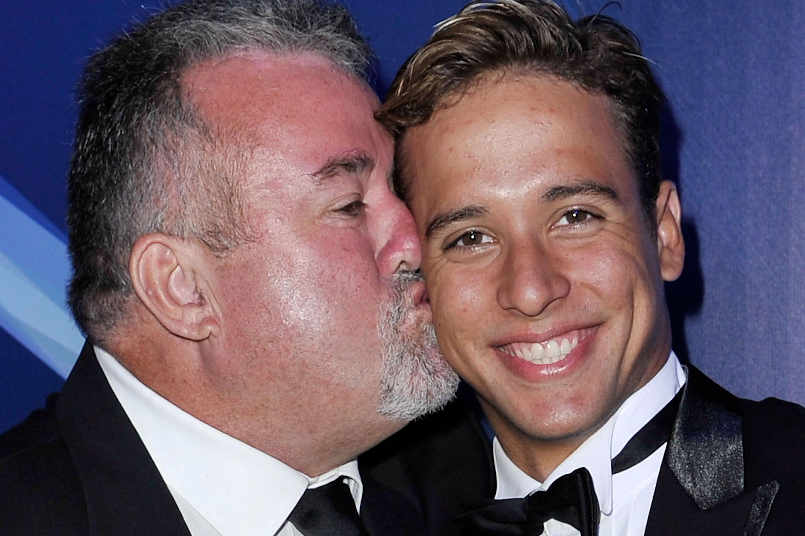 Bert kisses son Chad on the right cheek. They are both wearing black dinner suits.