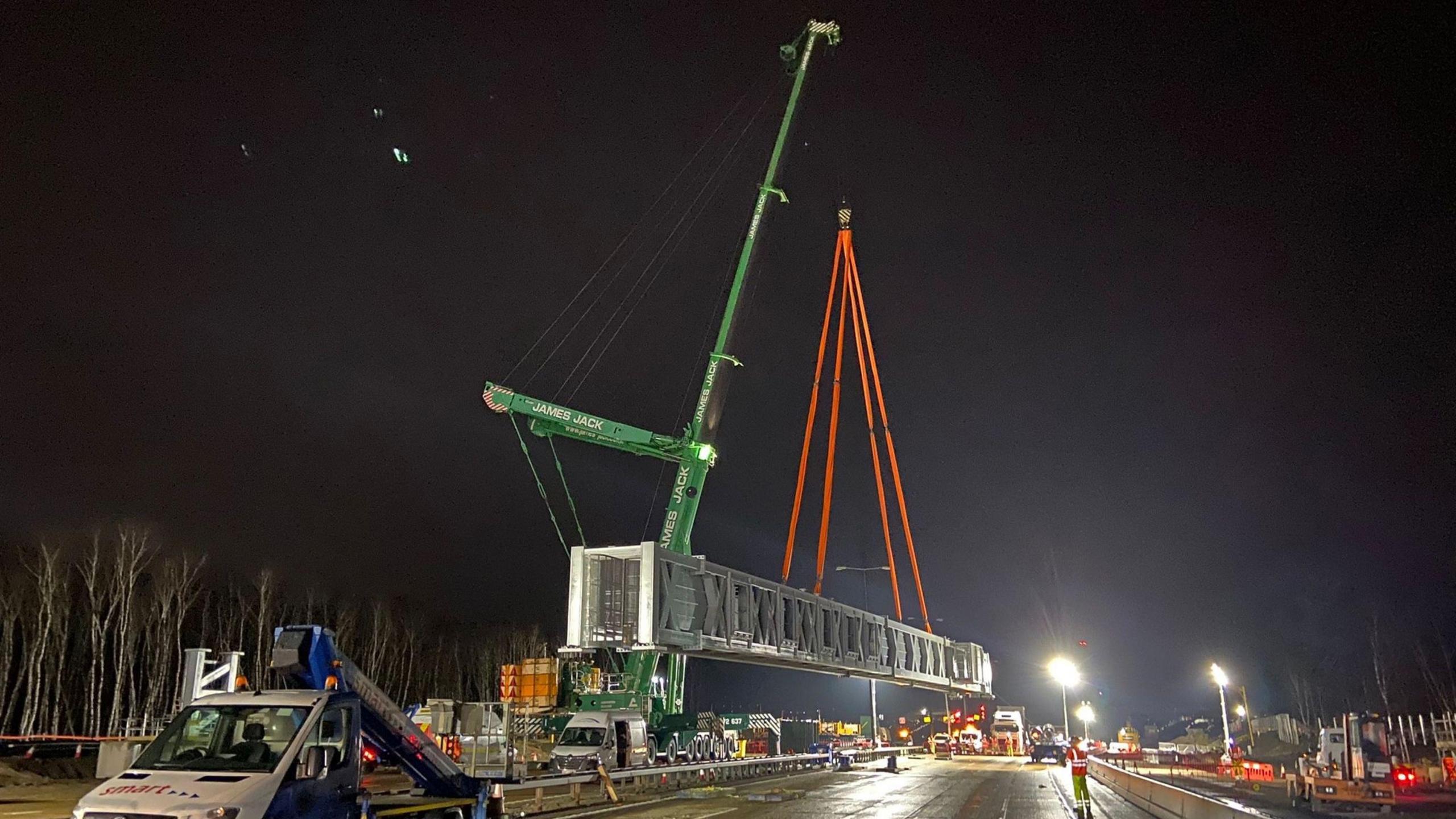 A gantry is suspended above the ground by a large crane