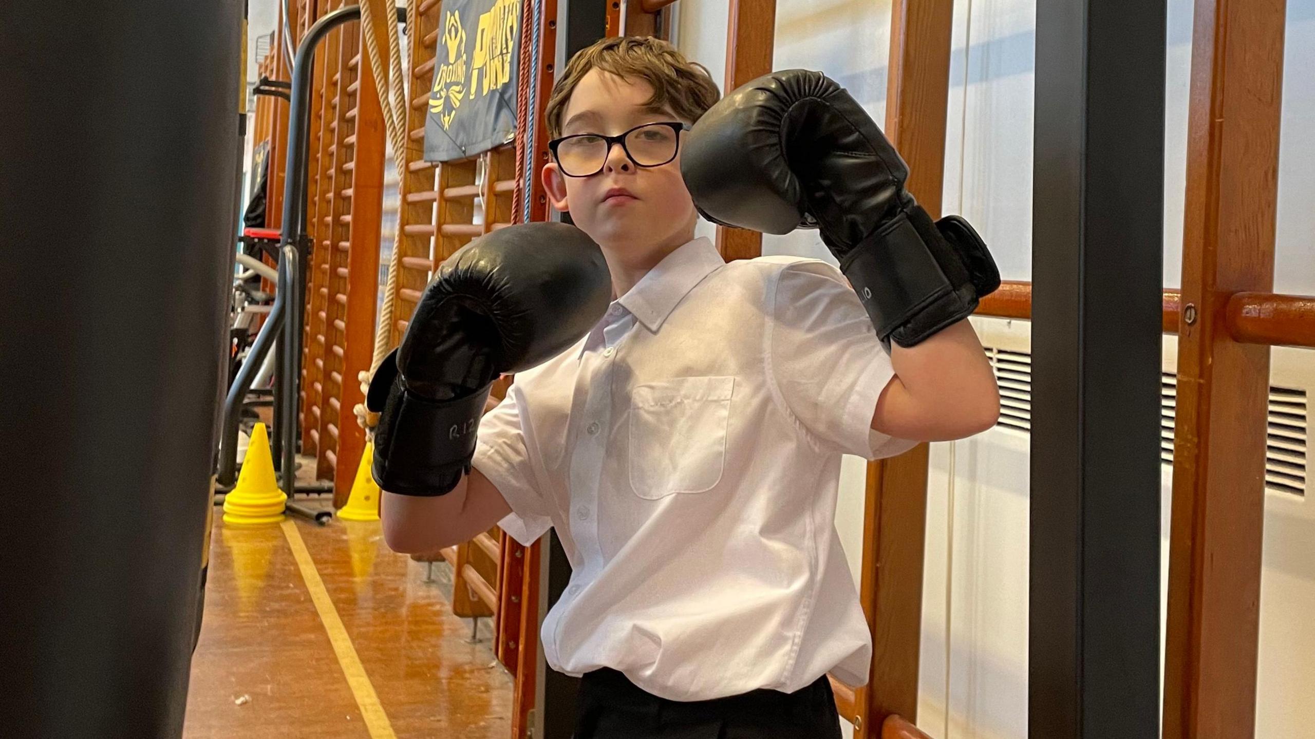 Lucas, in his school shirt, is stood with his boxing gloves up.