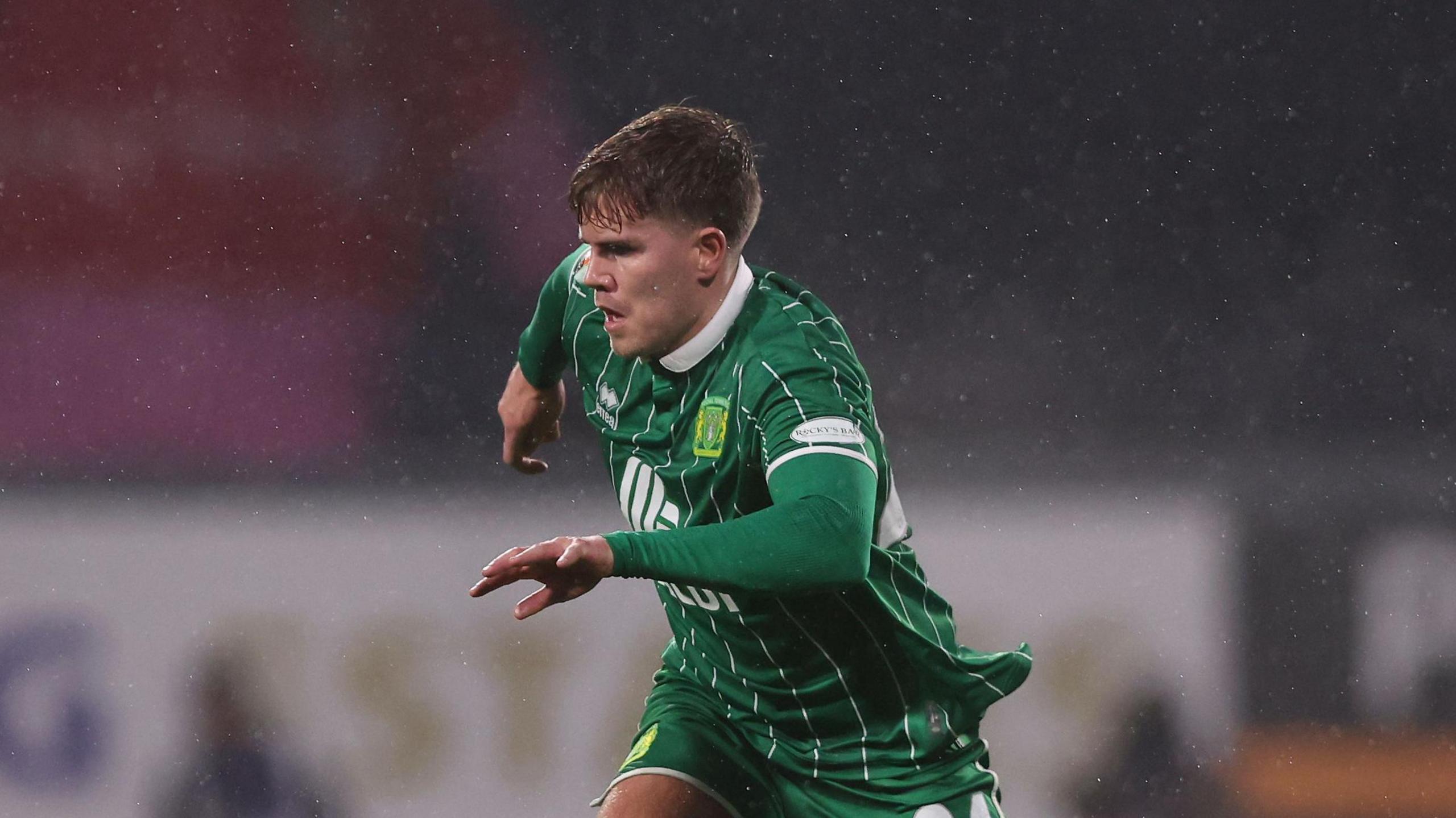 Charlie Cooper wearing a green and white Yeovil Town shirt in action during a game.